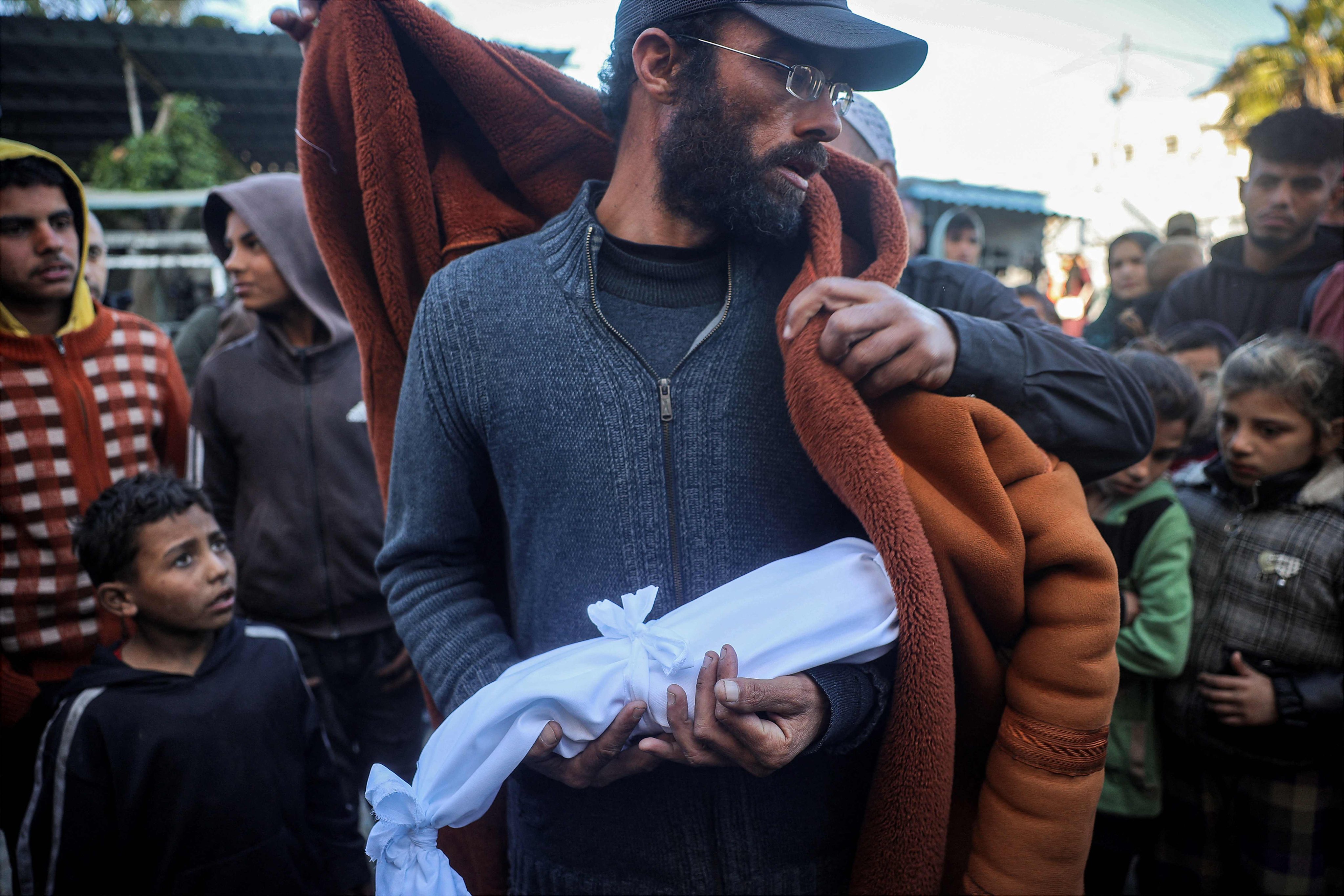 A father holds the blanket-wrapped body of his newborn, who reportedly died of hypothermia. Photo: AFP