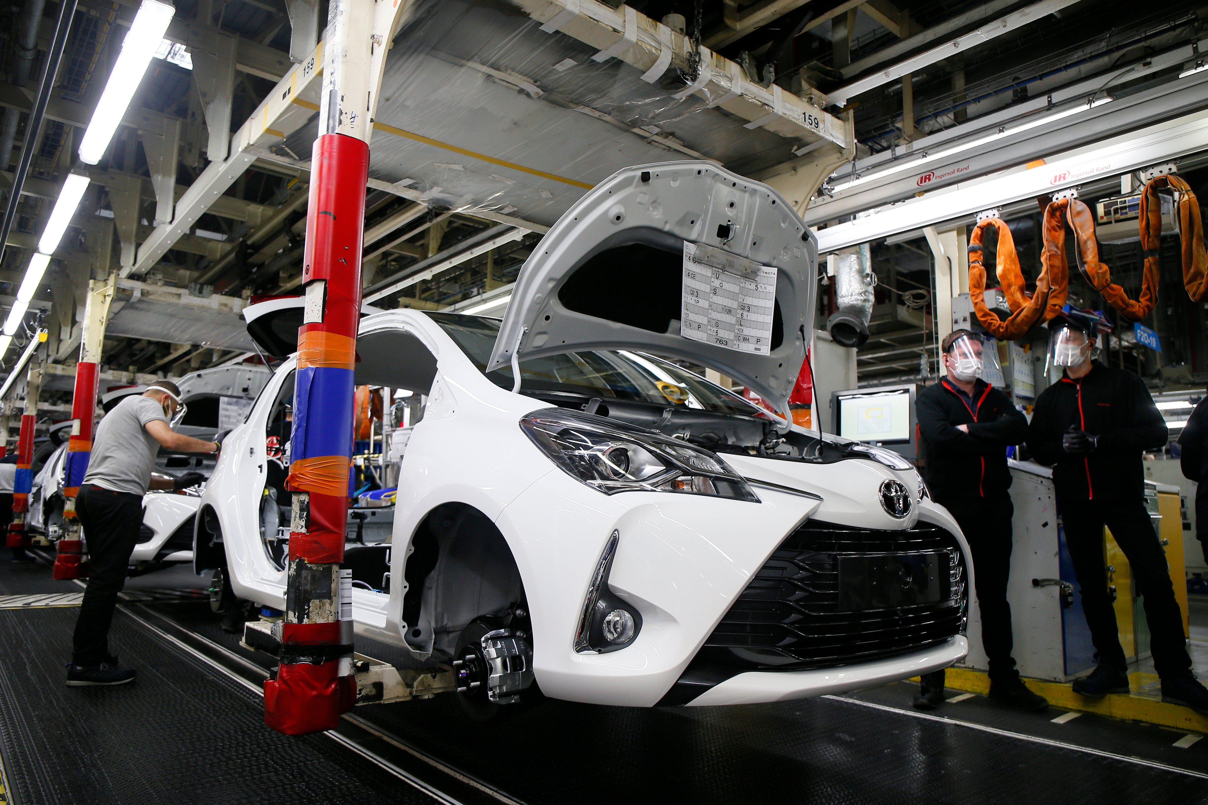 An employee wearing a face mask works on a Yaris car at a Toyota car factory in France. Photo: AP/File