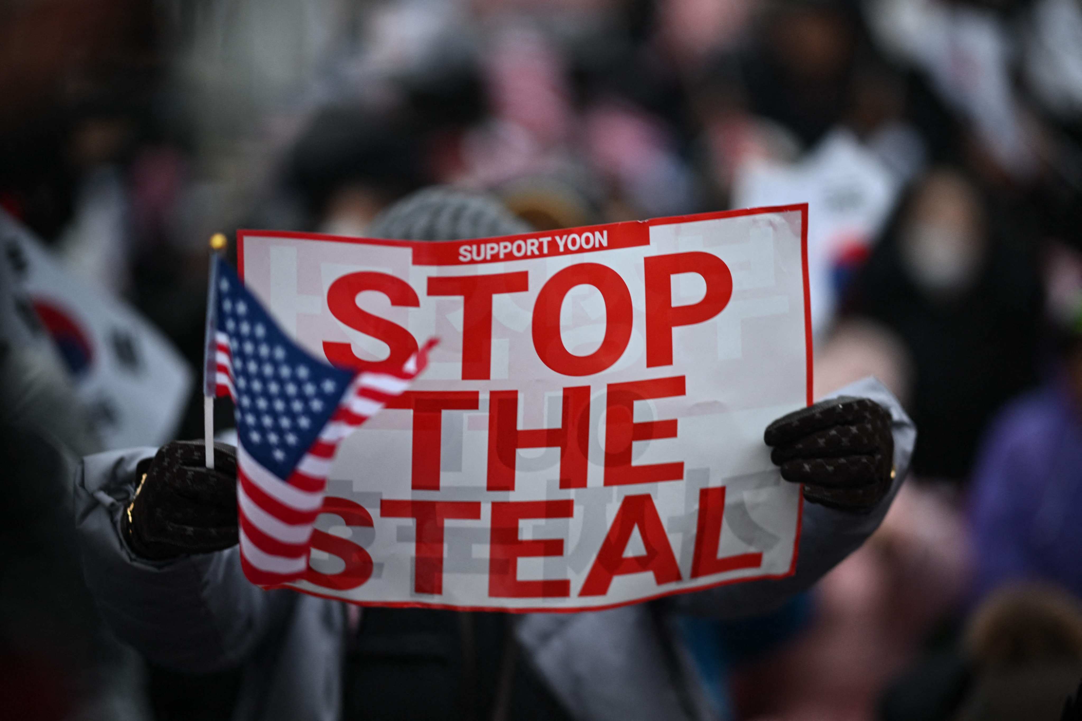 A supporter of South Korea’s impeached president Yoon Suk-yeol holds a “Stop the steal” sign during a rally near his residence in Seoul on Monday. Photo: AFP