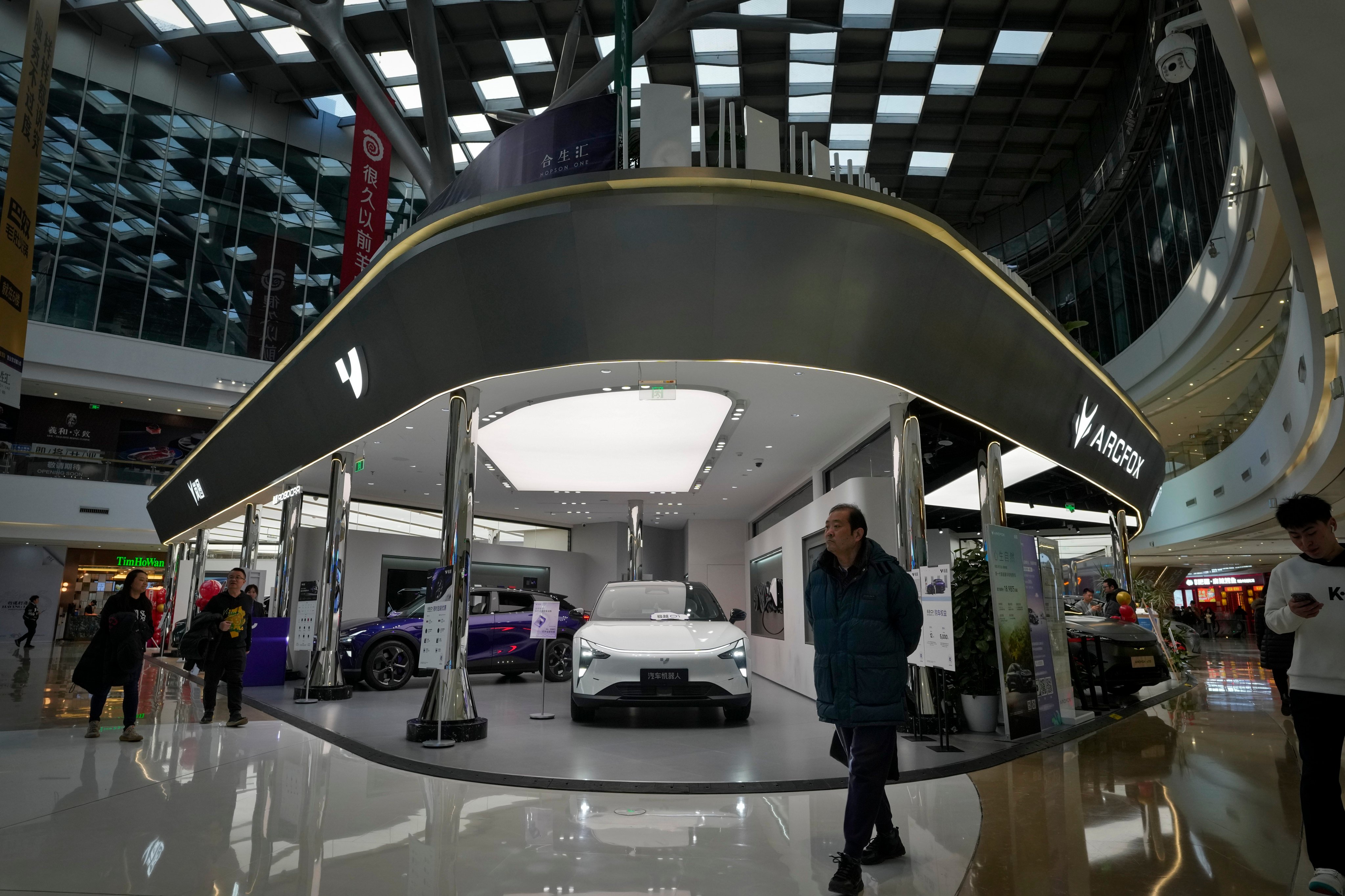 People walk past various Chinese-made electric cars for sale inside a shopping centre in Beijing on January 9, 2024. Photo: AP