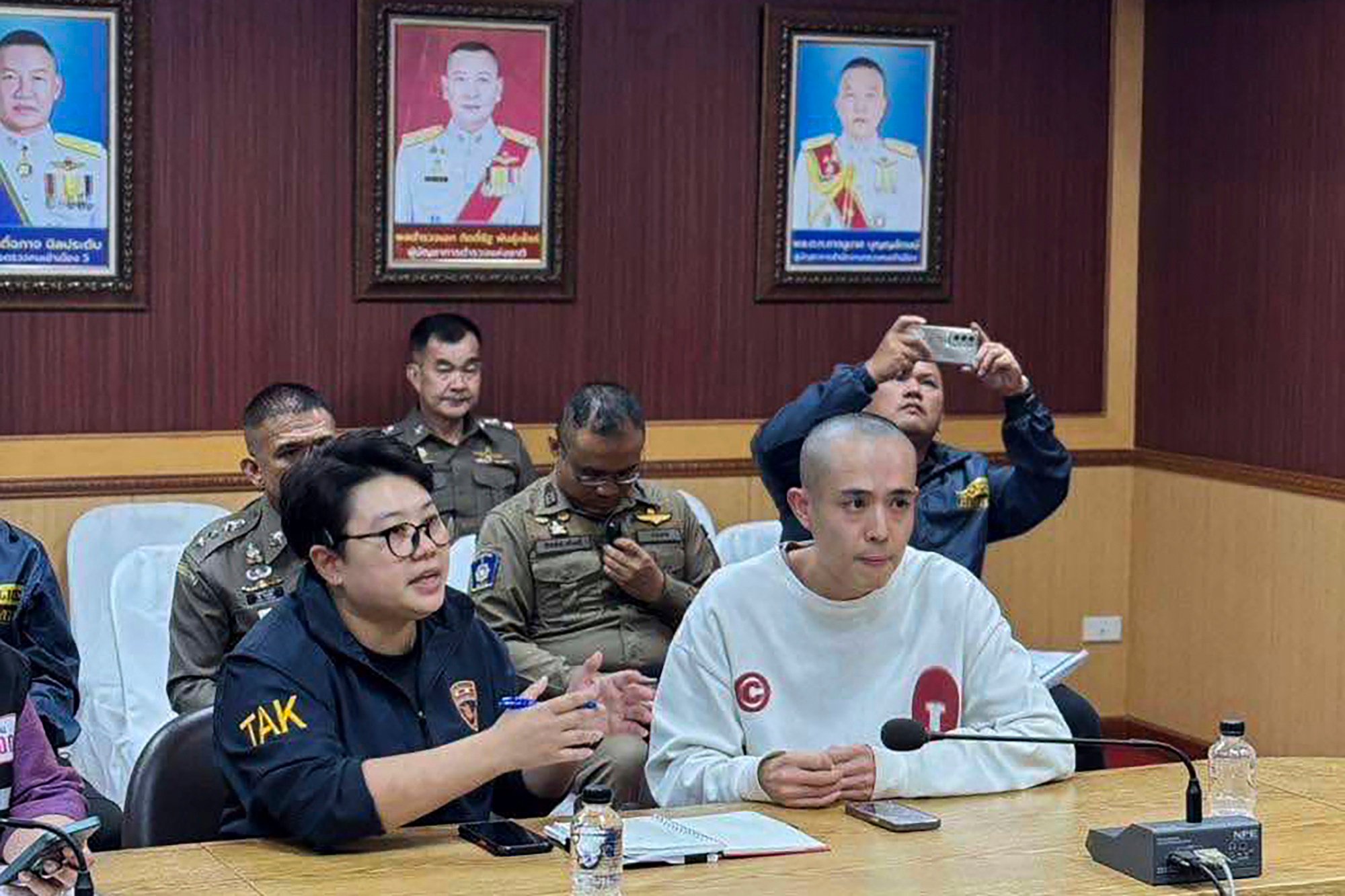 Chinese actor Wang Xing (right) speaks with Thai police officers in Mae Sot district, Thailand on Tuesday after being rescued from a scam compound in Myanmar. Photo: The Royal Thai Police via AP