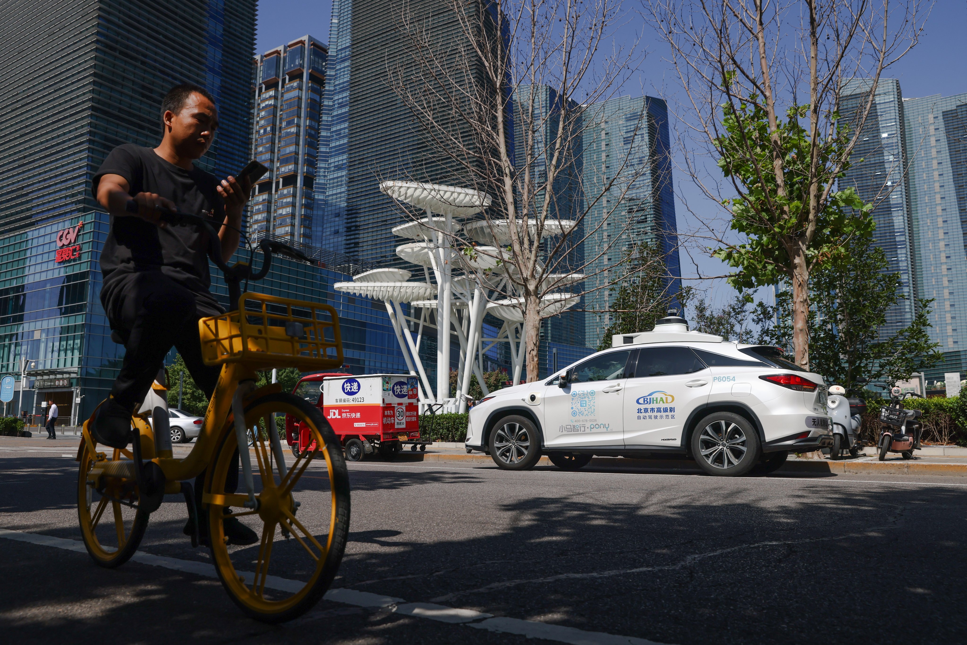 A man rides his bike opposite a self-driving taxi in the Daxing district in Beijing, China, September 2, 2024. Photo: EPA-EFE