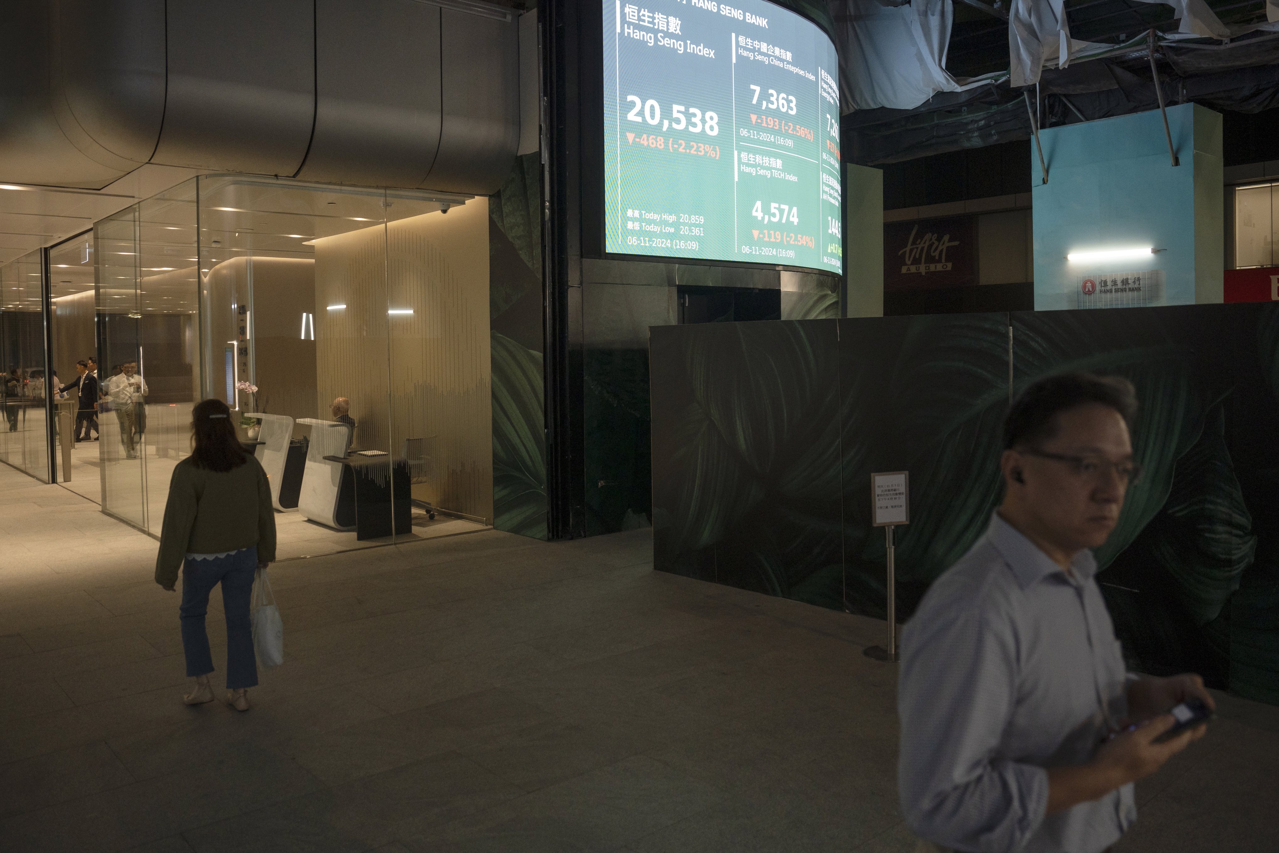 Pedestrians walk past a screen showing the Hang Seng index in Hong Kong on November 6, 2024. Photo: EPA-EFE