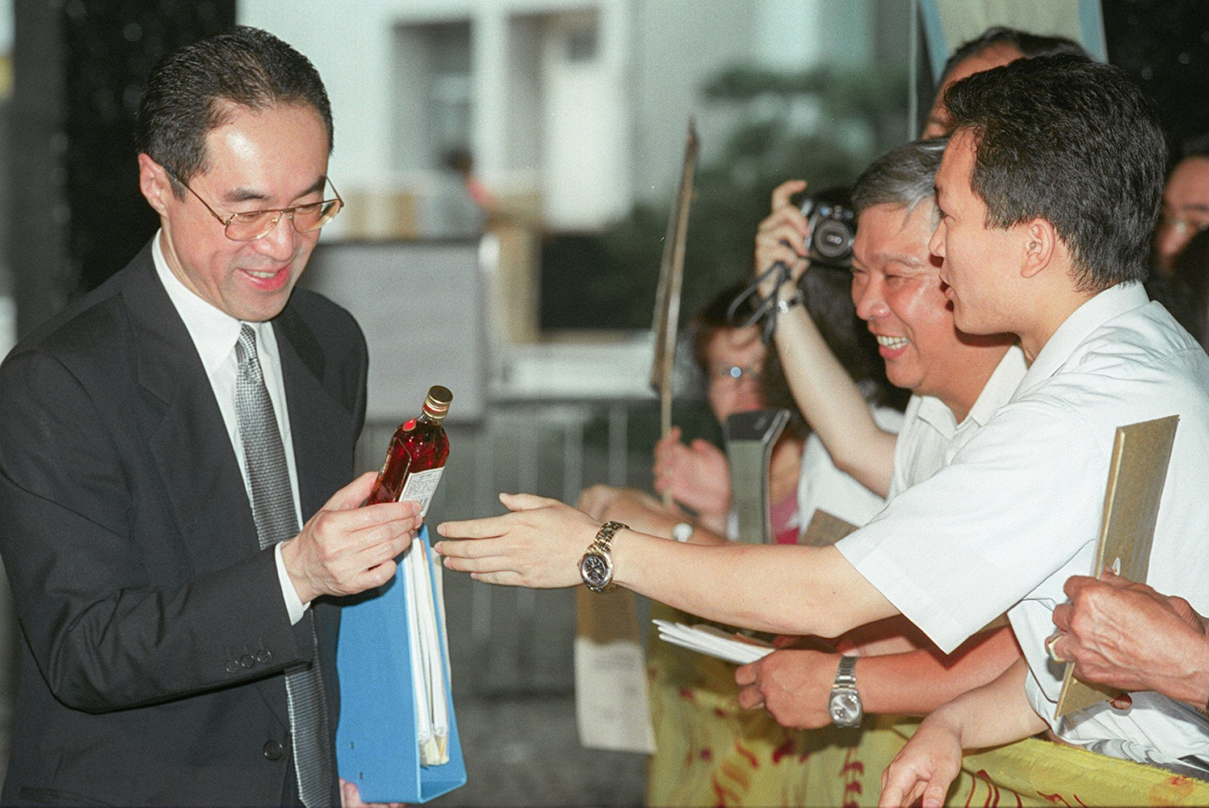 Executive council member Henry Tang is handed a bottle of Chinese medicinal wine by workers at a local production plant in 1998. Photo: SCMP Archives