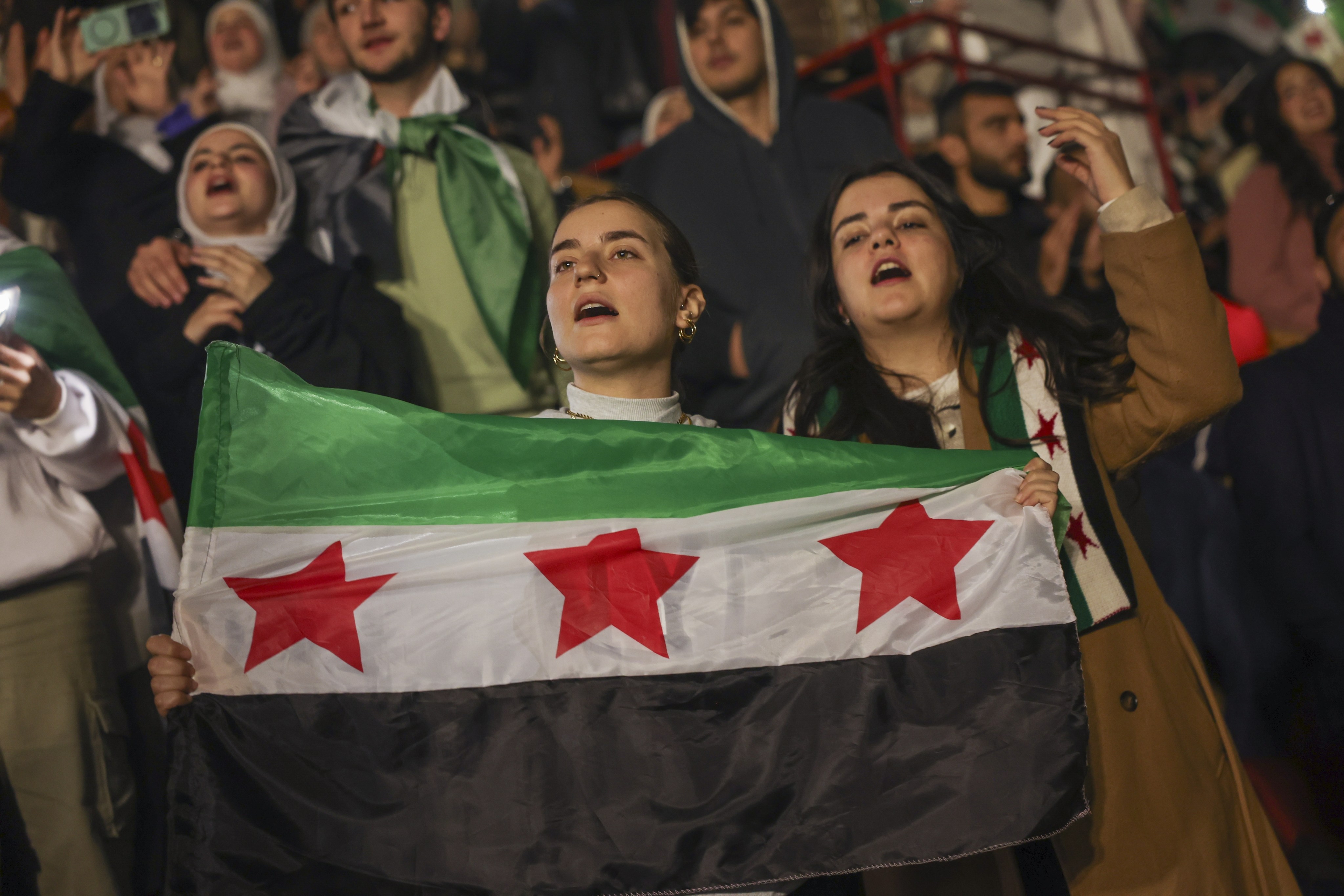 Syrians sing and hold a post-Assad flag during a concert by the recently returned ‘revolutionary’ singer Wasfi Maasrani, in Damascus on Wednesday. Photo: AP