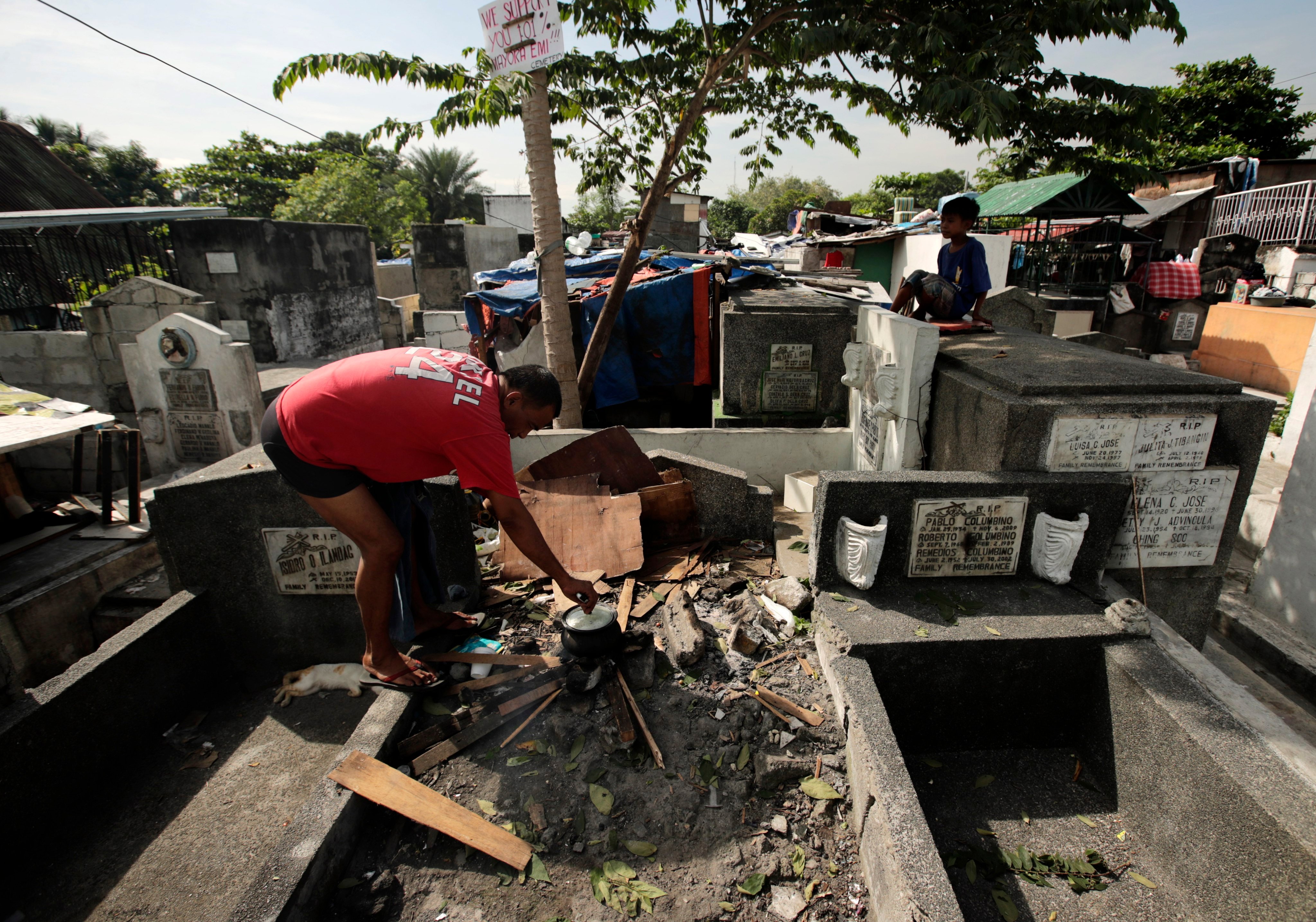 A Filipino grave dweller cooks food on top of a tomb at a cemetery in Manila, the Philippines. Photo: EPA-EFE