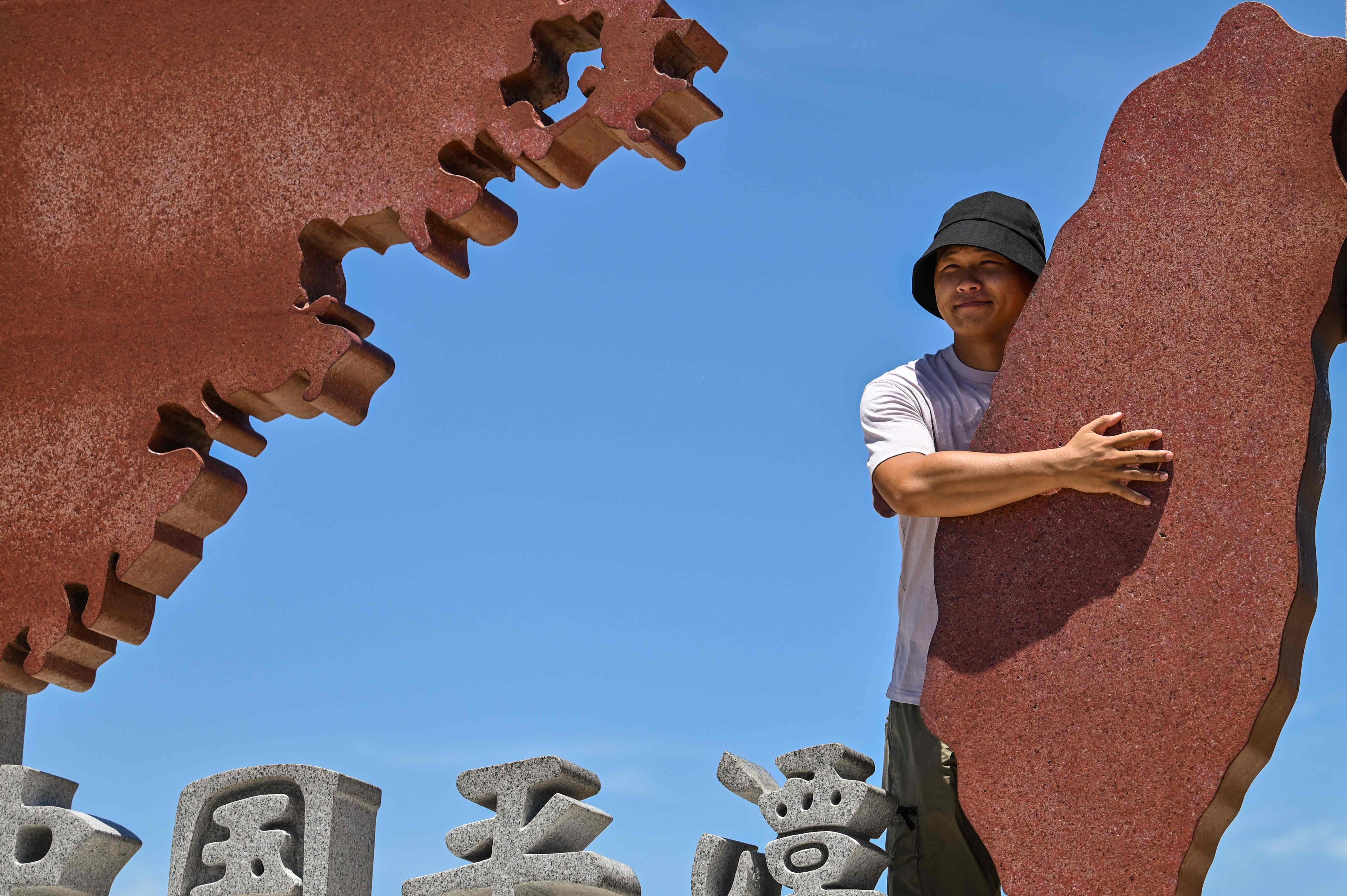 A tourist in Fujian’s Pingtan county poses with a monument representing mainland China and Taiwan. Photo: AFP