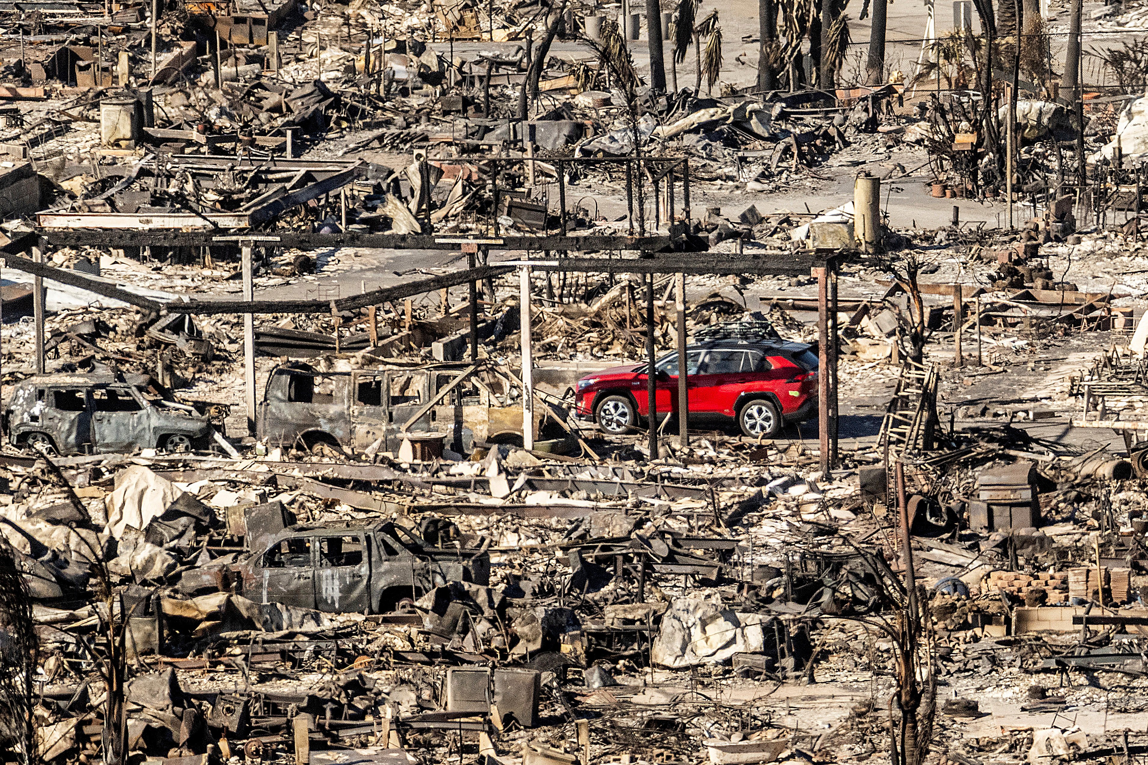 A car drives past homes and vehicles destroyed by the Palisades Fire. Photo: AP