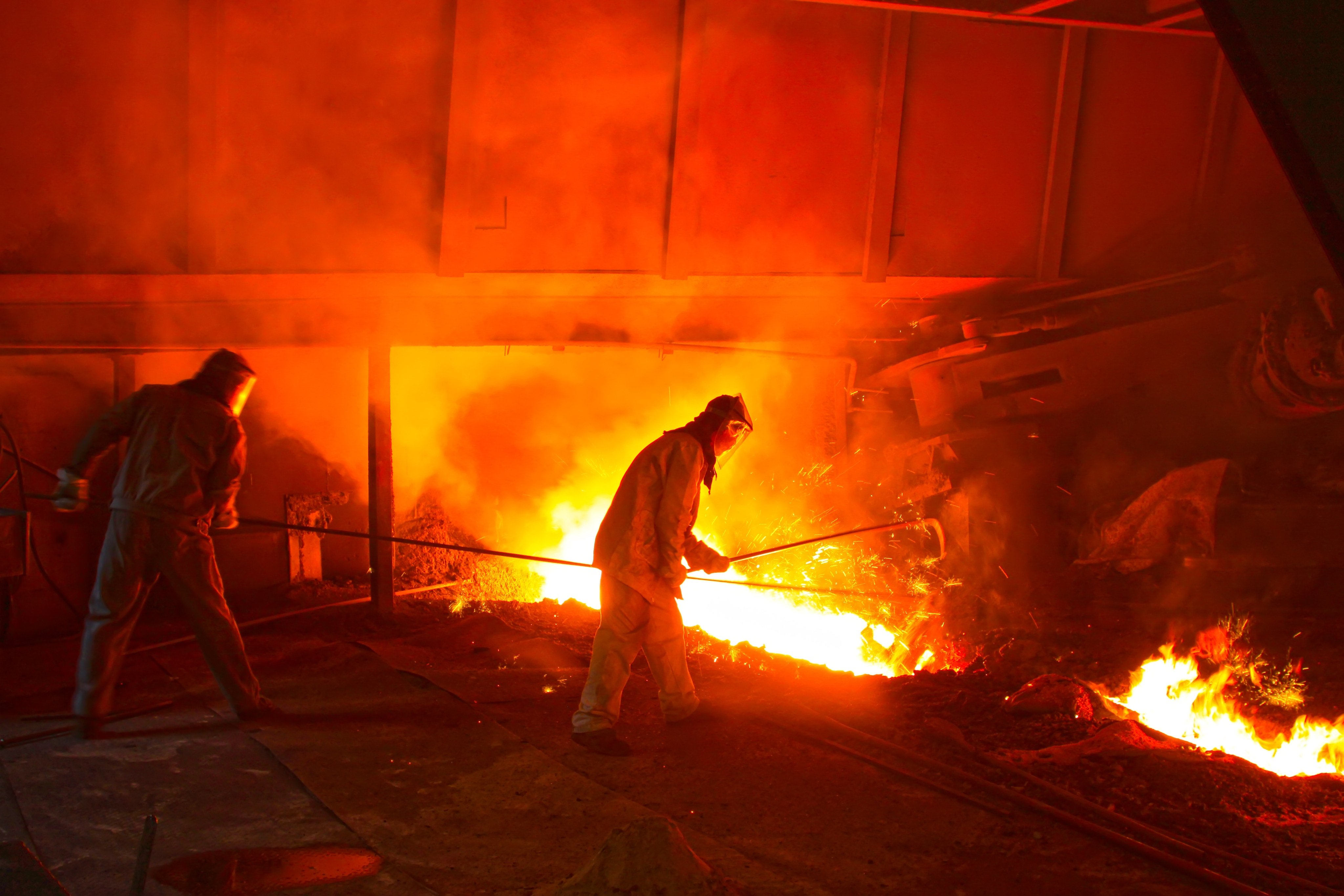 Ironworkers stand in front of a blast furnace. Photo: Shutterstock