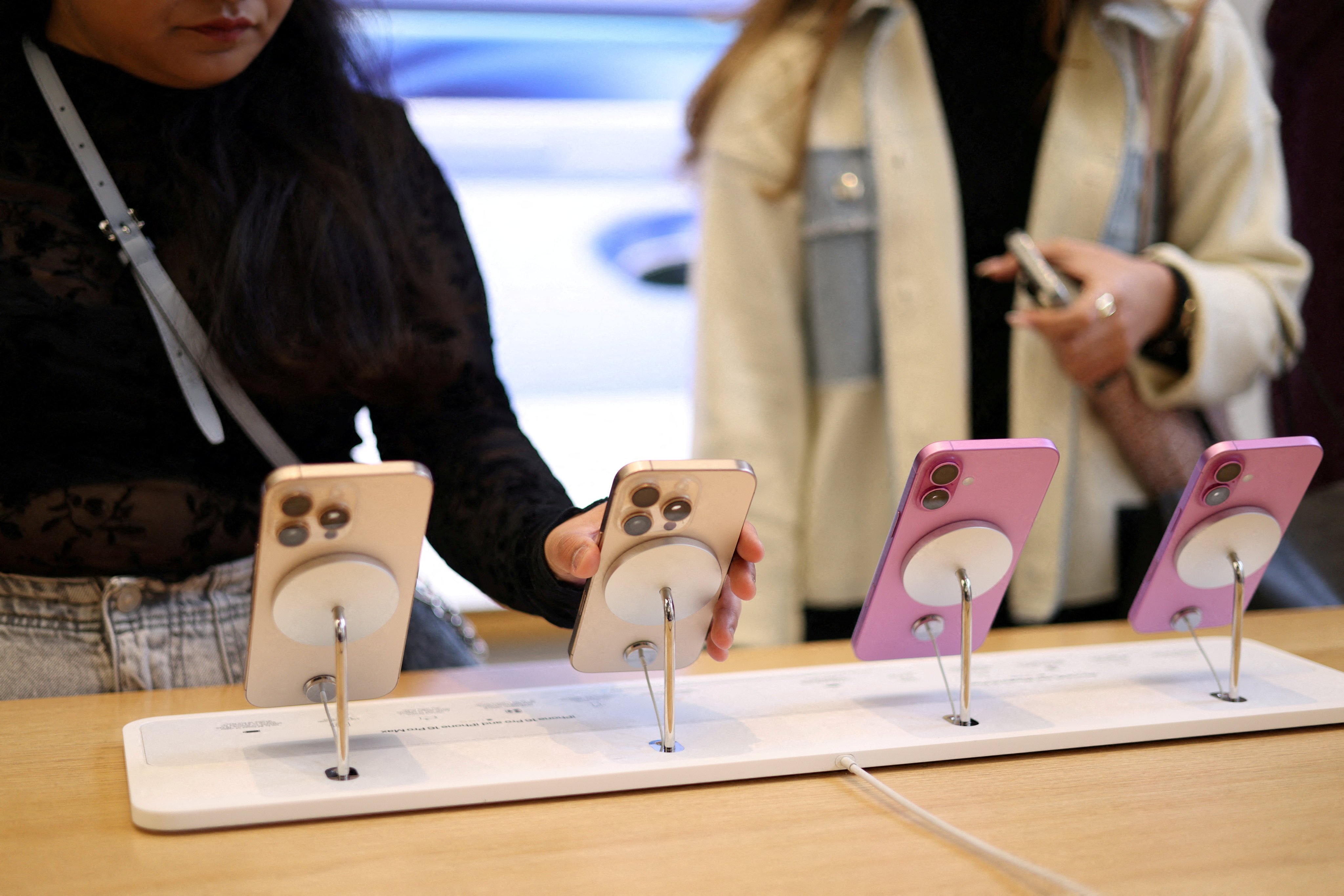 Women check out the iPhone 16 at an Apple Store in London on October 6, 2024. Sales of the company’s latest handset helped push to the top of the market in the fourth quarter. Photo: Reuters