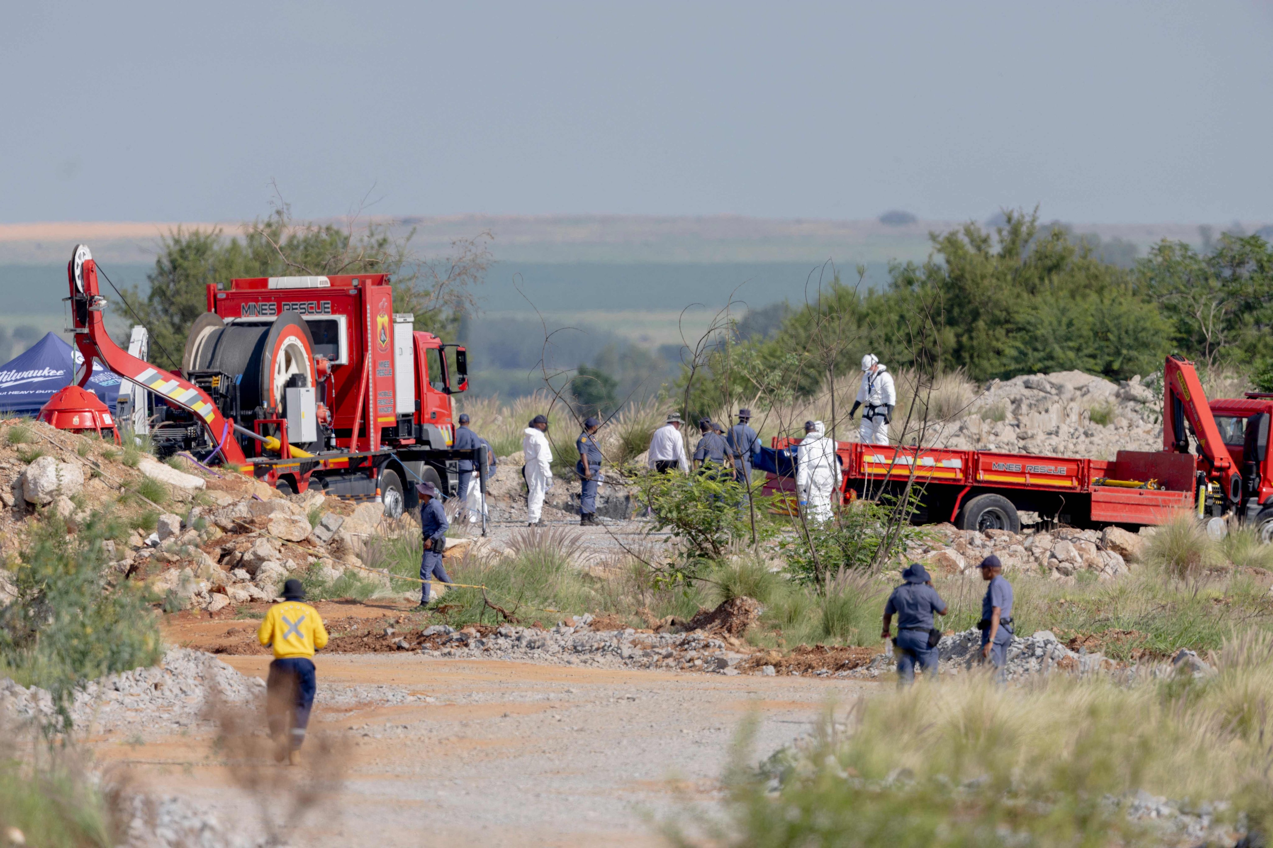 Rescuers and South African Police Service officers carry remains in blue body bags. Photo: AFP