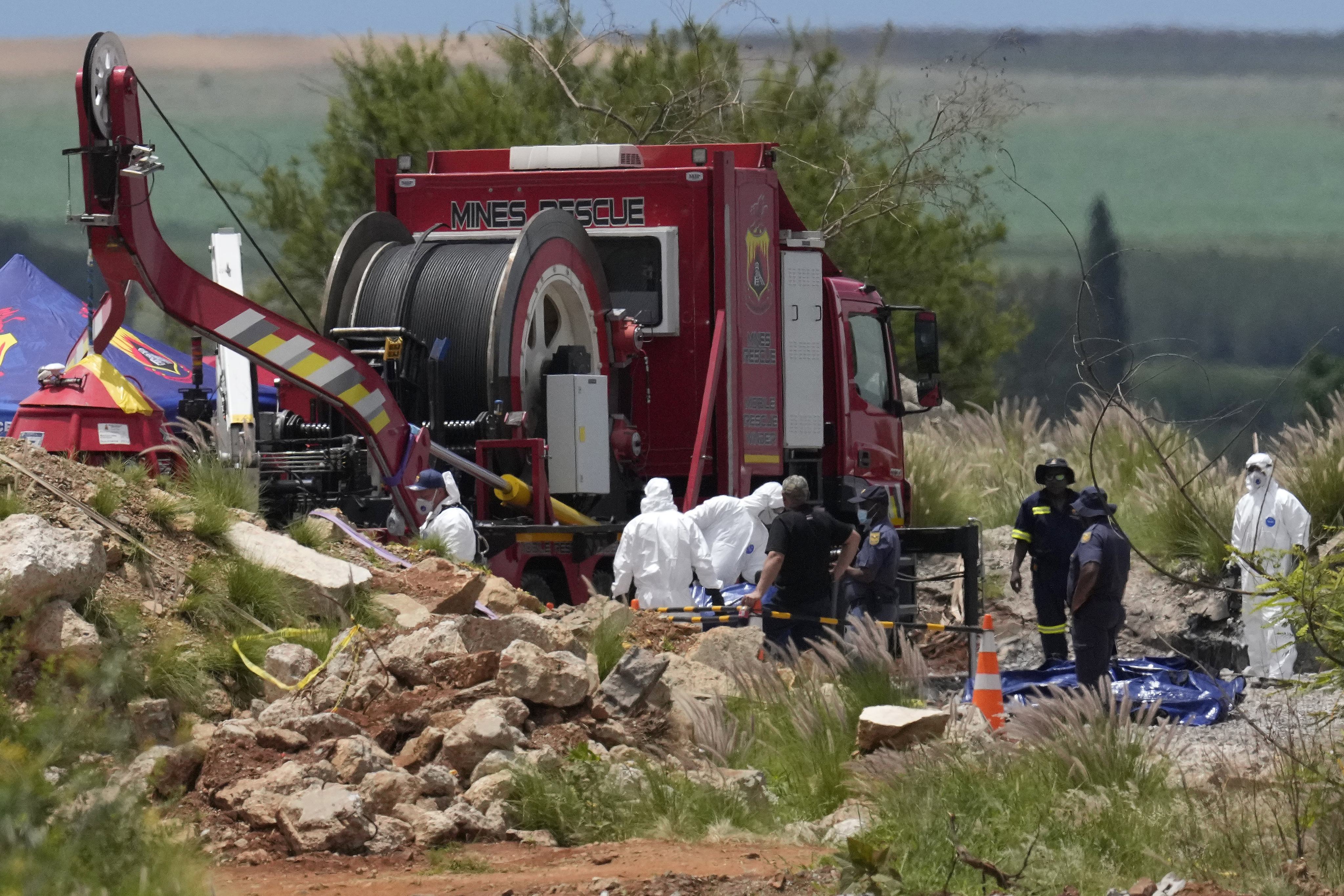 Forensic service workers carry body remains in blue body bags. Photo: AP