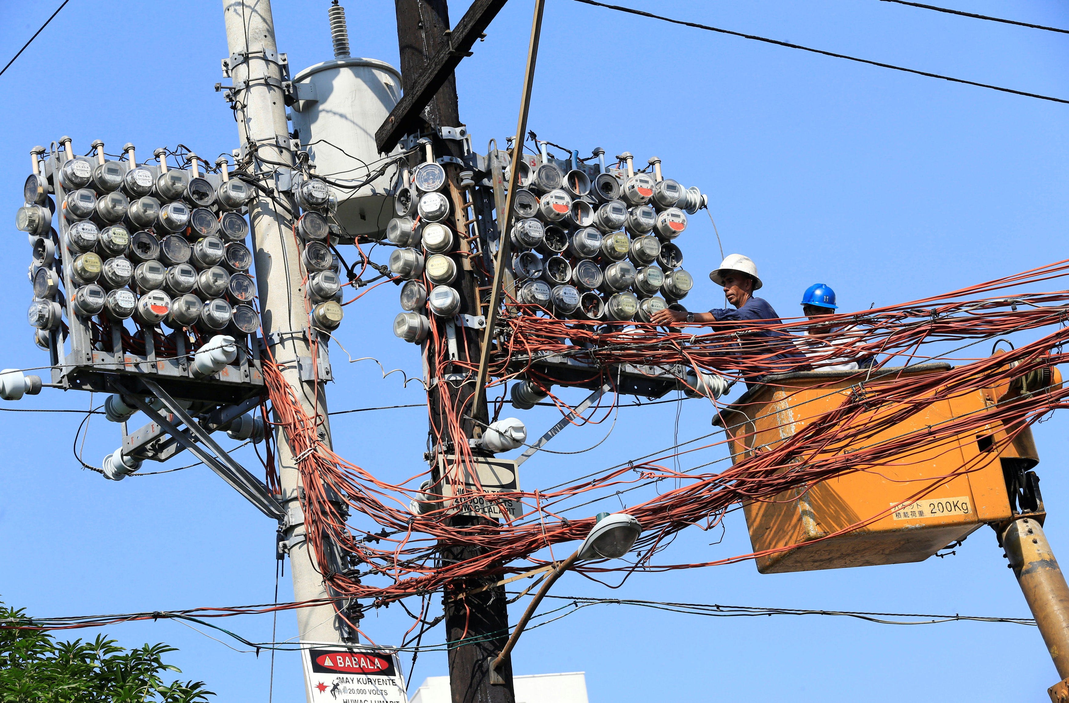 Filipino lineworkers repair power meters atop an electricity post at the main street of Quiapo city, Metro Manila, the Philippines, in 2017. Photo: Reuters