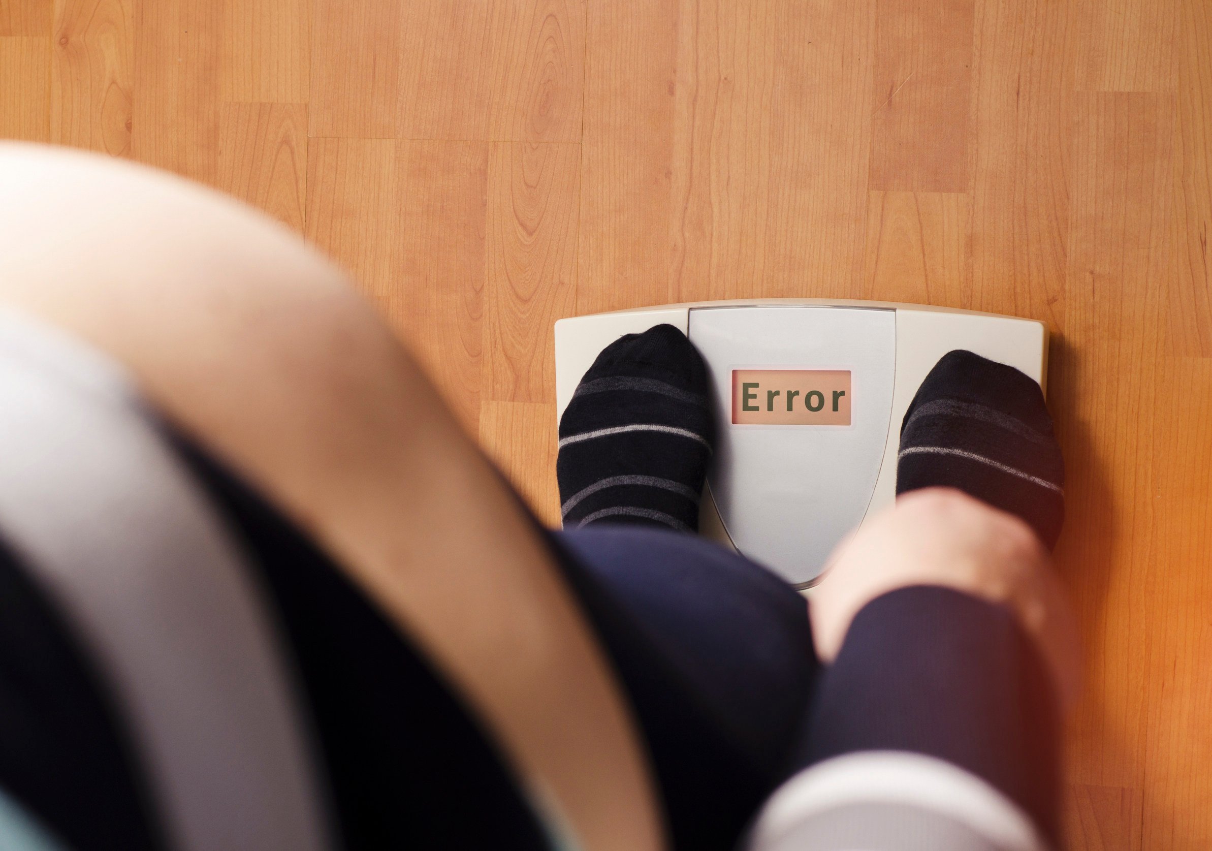 An overweight person standing on a digital weight scale. Photo: Shutterstock