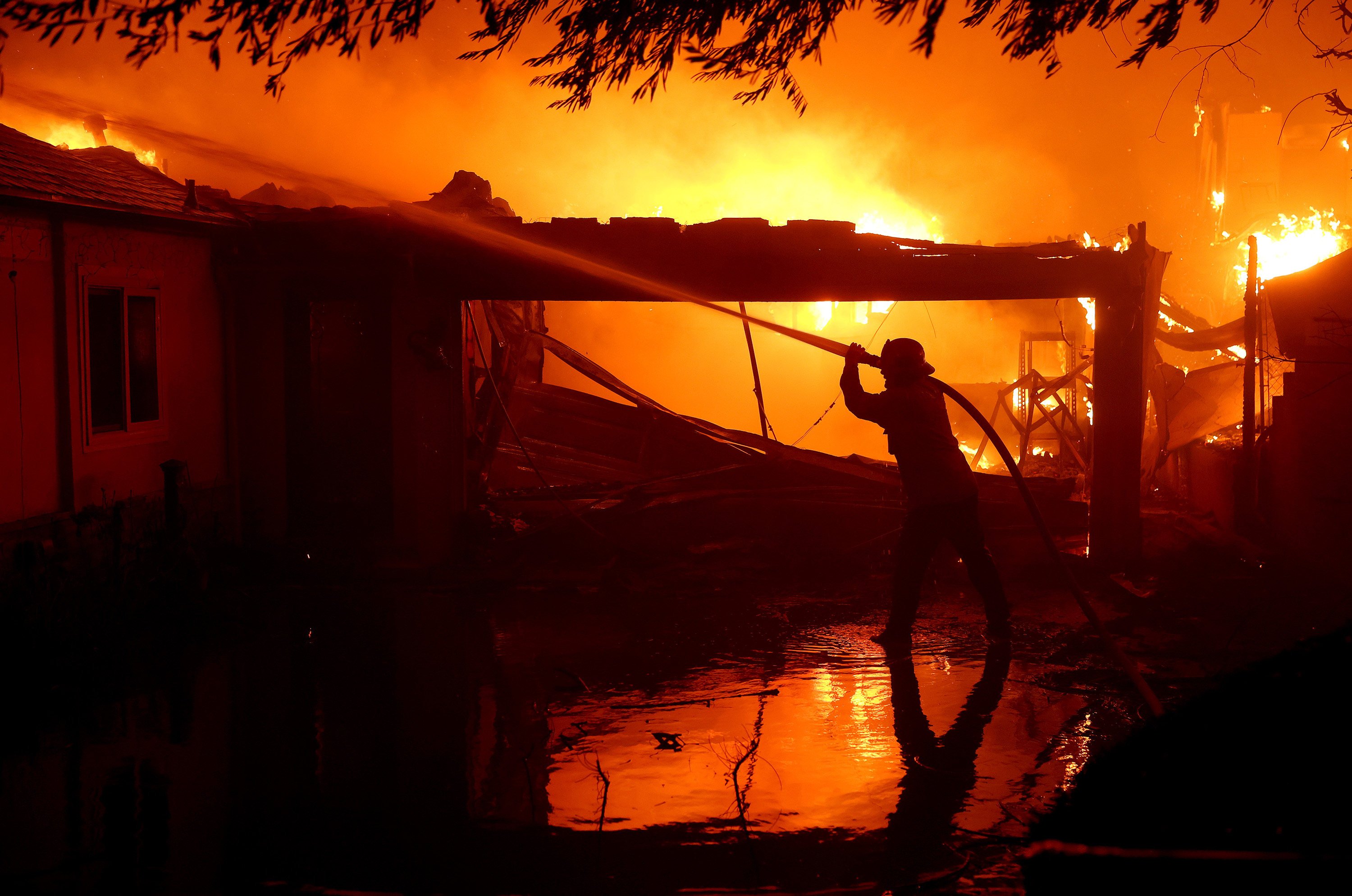 A firefighter sprays water on a burning home while battling the Eaton fire on January 8, 2025, in Altadena, California. Photo: Getty Images