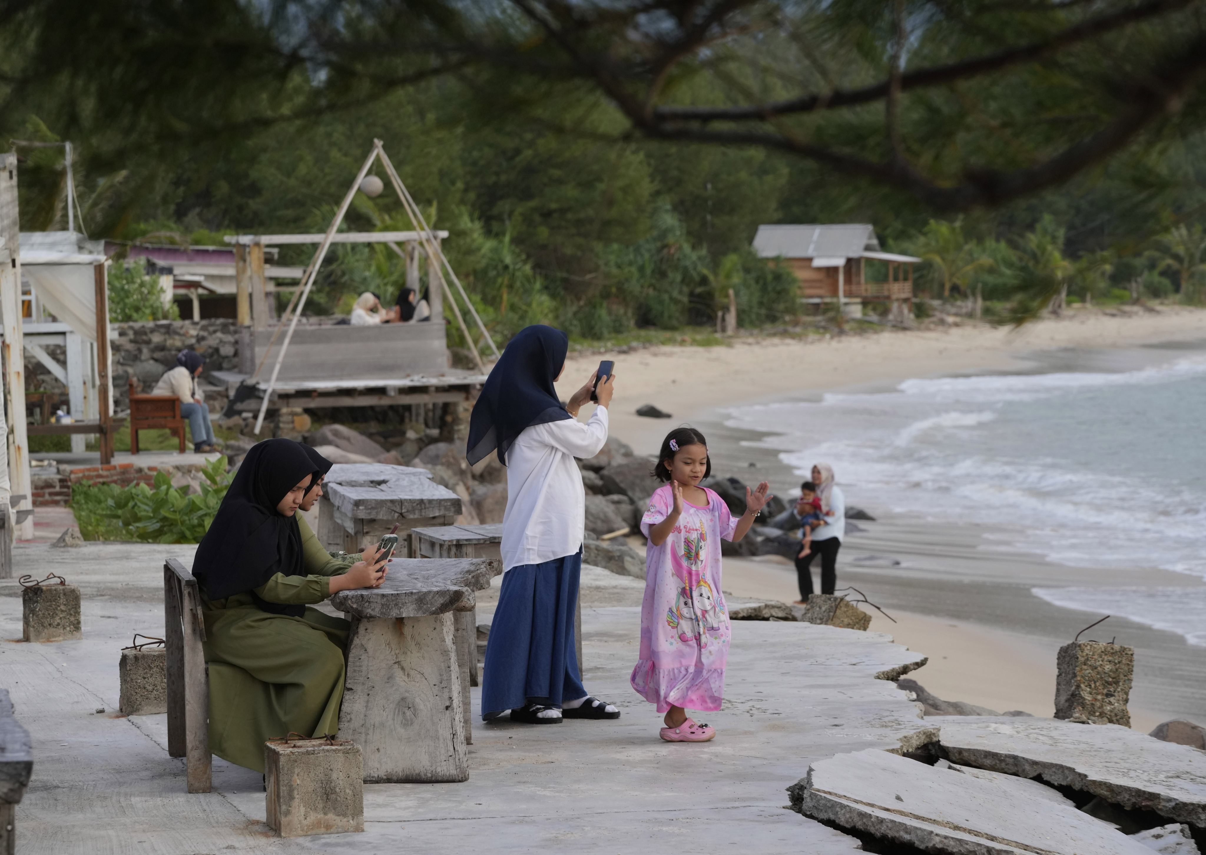 Young girls use their mobile phones as they visit Lampuuk beach on the outskirts of Banda Aceh, Indonesia, in December 2024. Photo: AP