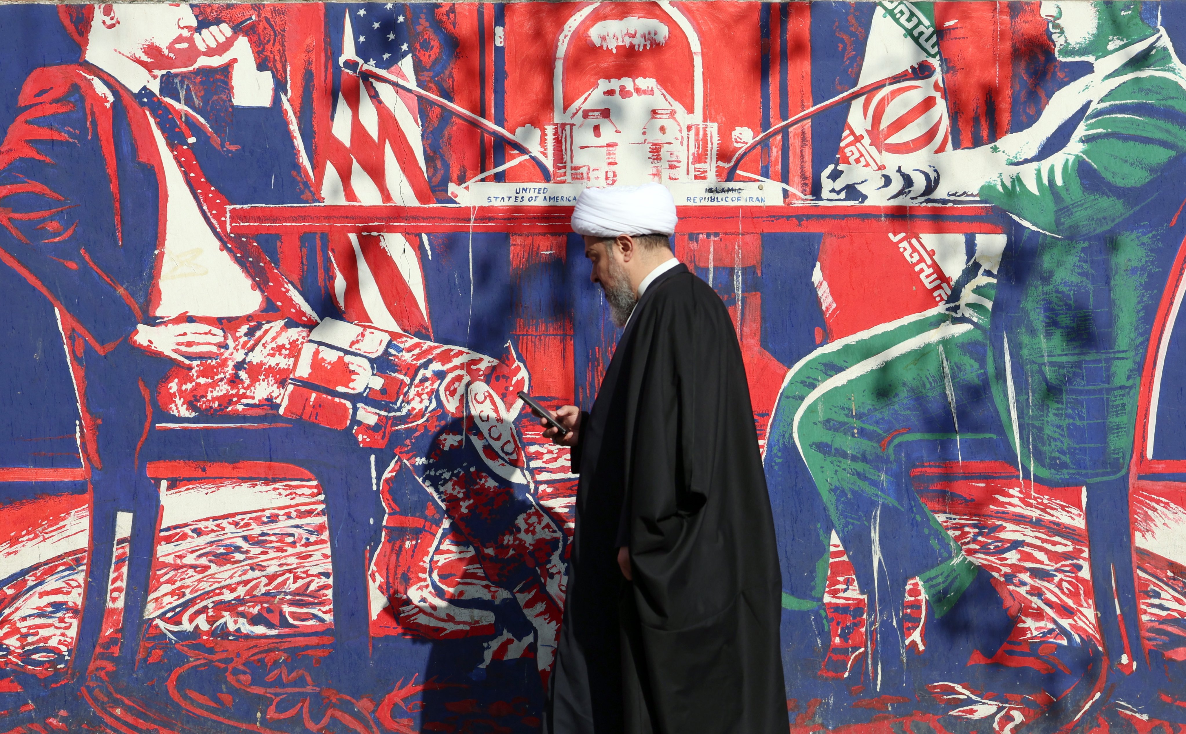 An Iranian cleric walks next to an anti-US mural in Tehran, Iran, on Wednesday. Photo: EPA-EFE