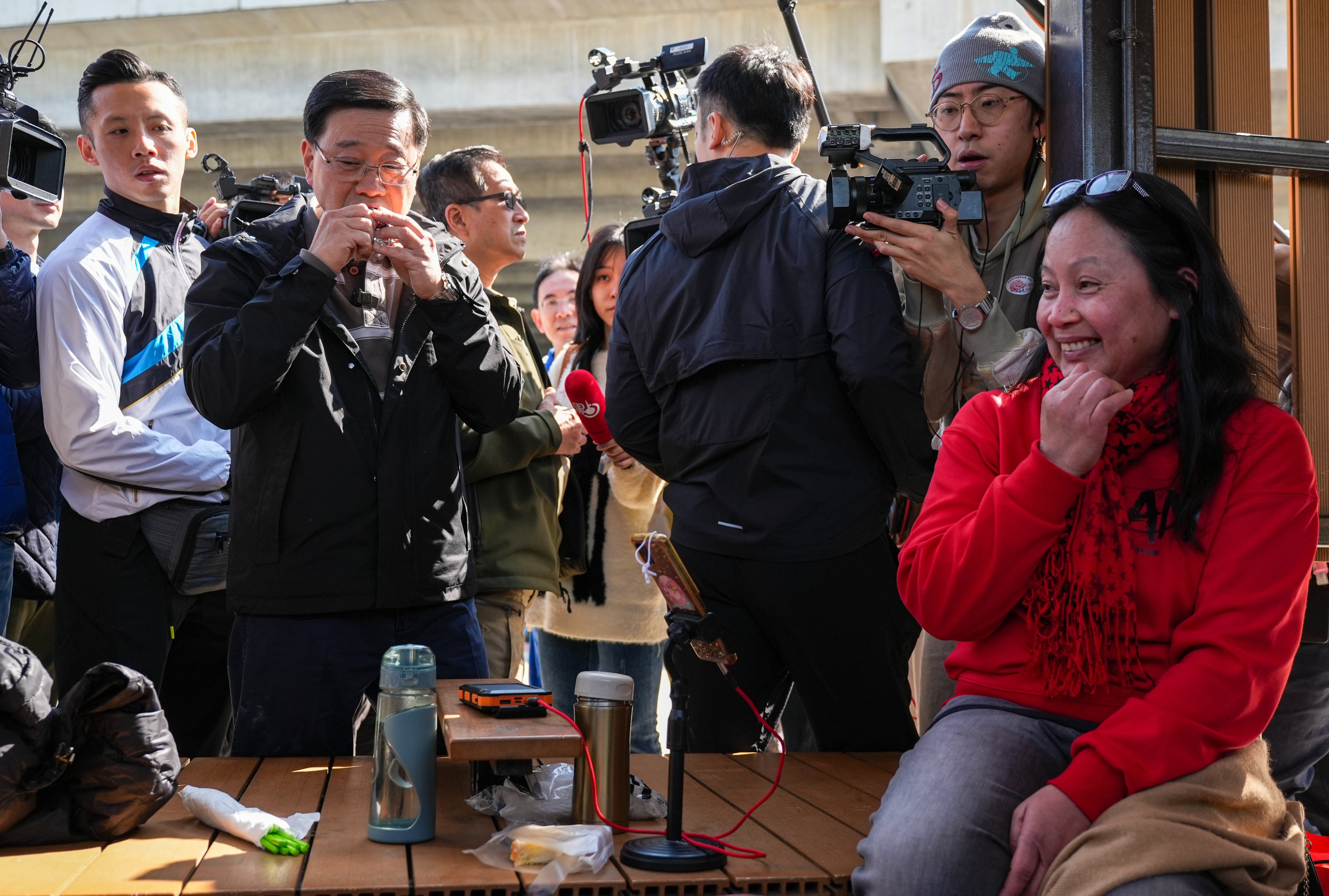 Chief Executive John Lee takes a bite of some sticky rice dessert as he chats with domestic helpers. Photo: Eugene Lee