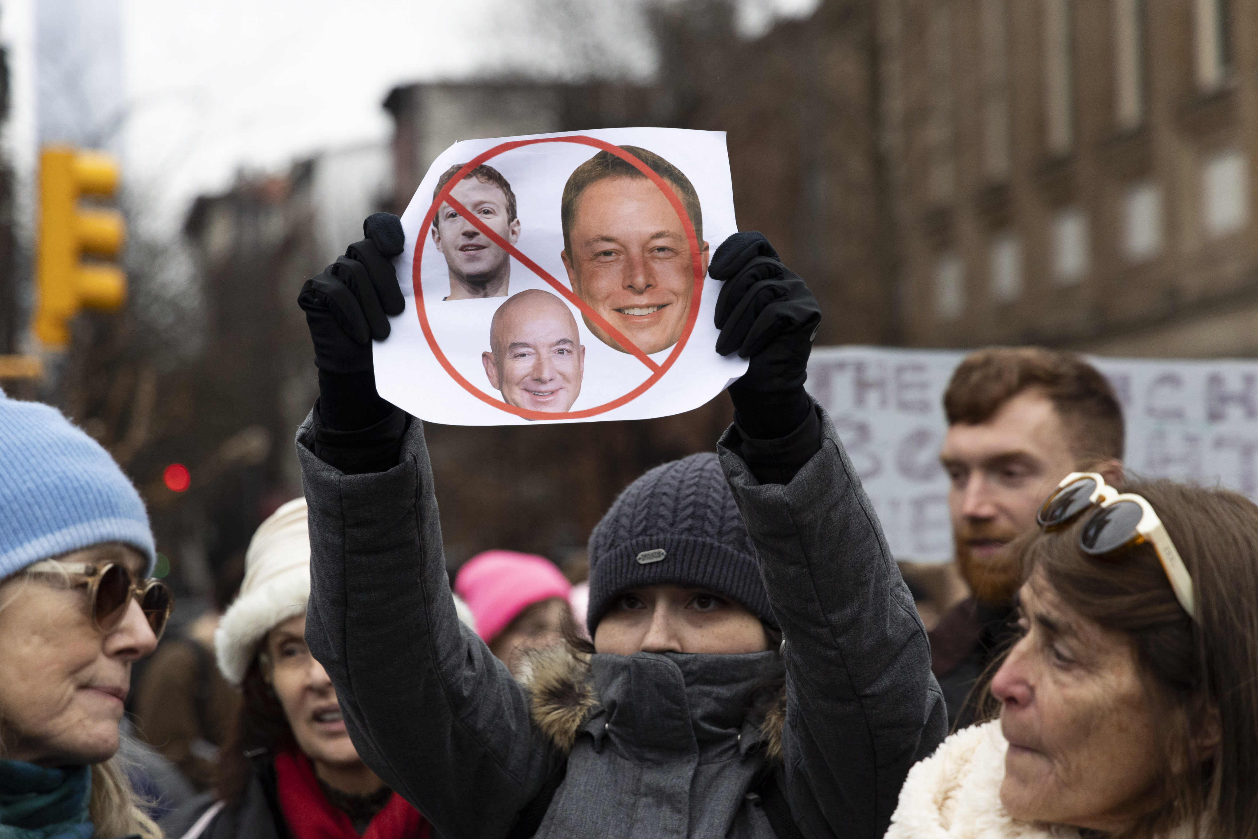 A protester holds a sign with the faces of Elon Musk, Mark Zuckerberg and Jeff Bezos at a rally in Washington to protest the policies of the incoming Trump administration. Photo: Gina M Randazzo/ZUMA Press Wire/dpa