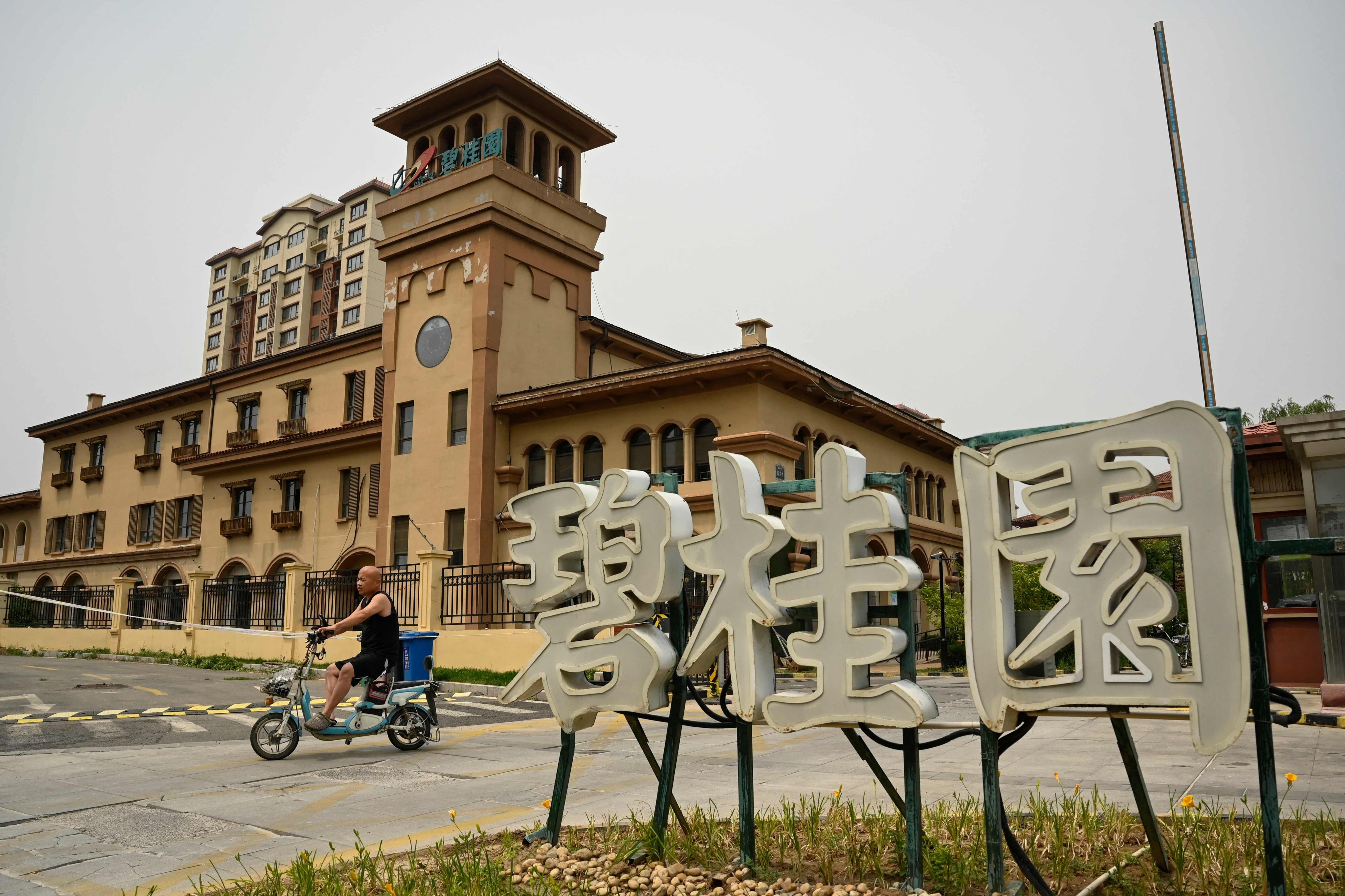 A man rode a scooter past a Country Garden housing complex in Tianjin. Photo: AFP 