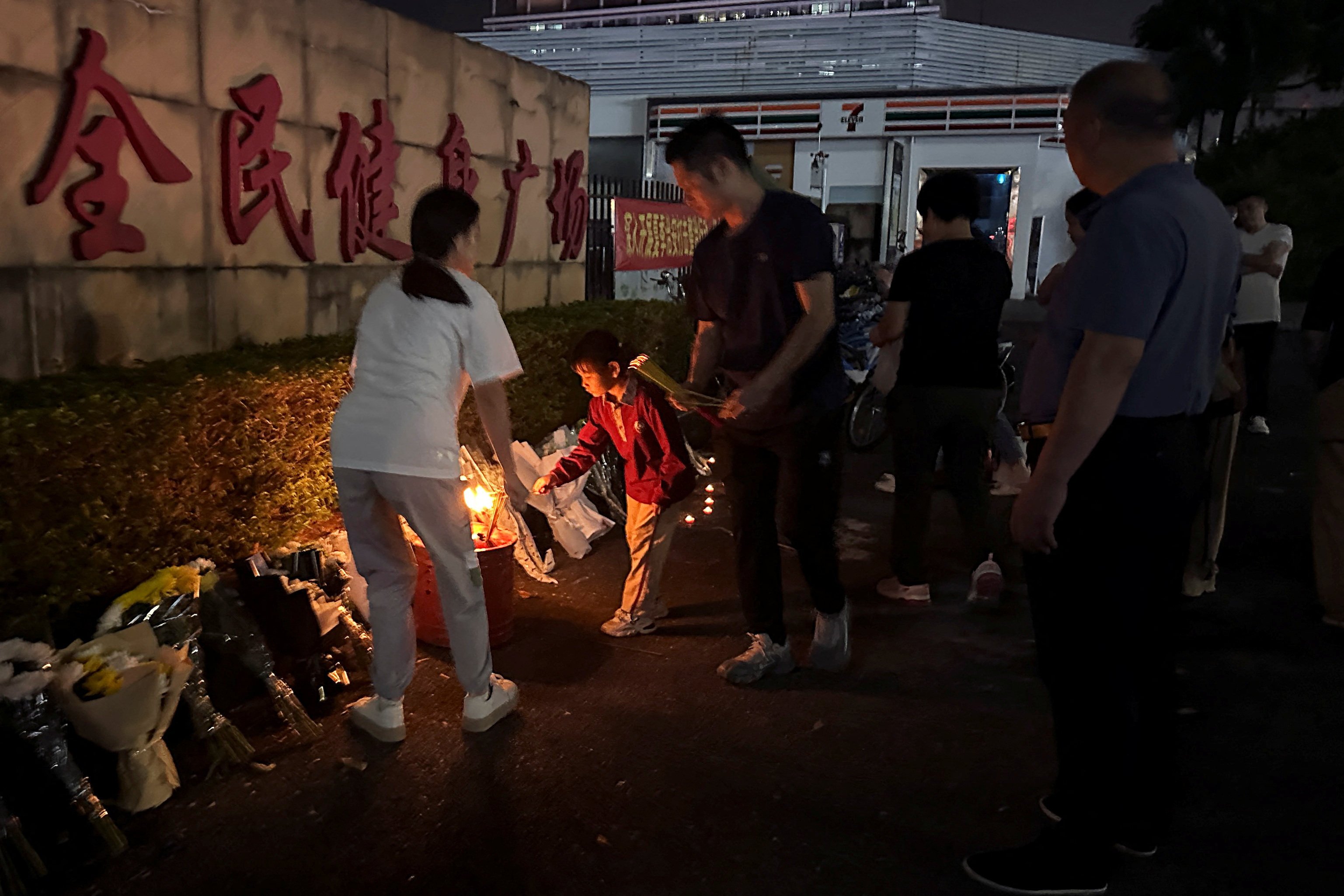 People burn incense near floral tributes placed outside a sports centre on November 12, the day after a deadly hit-and-run attack in Zhuhai, southern China. Photo: Reuters 