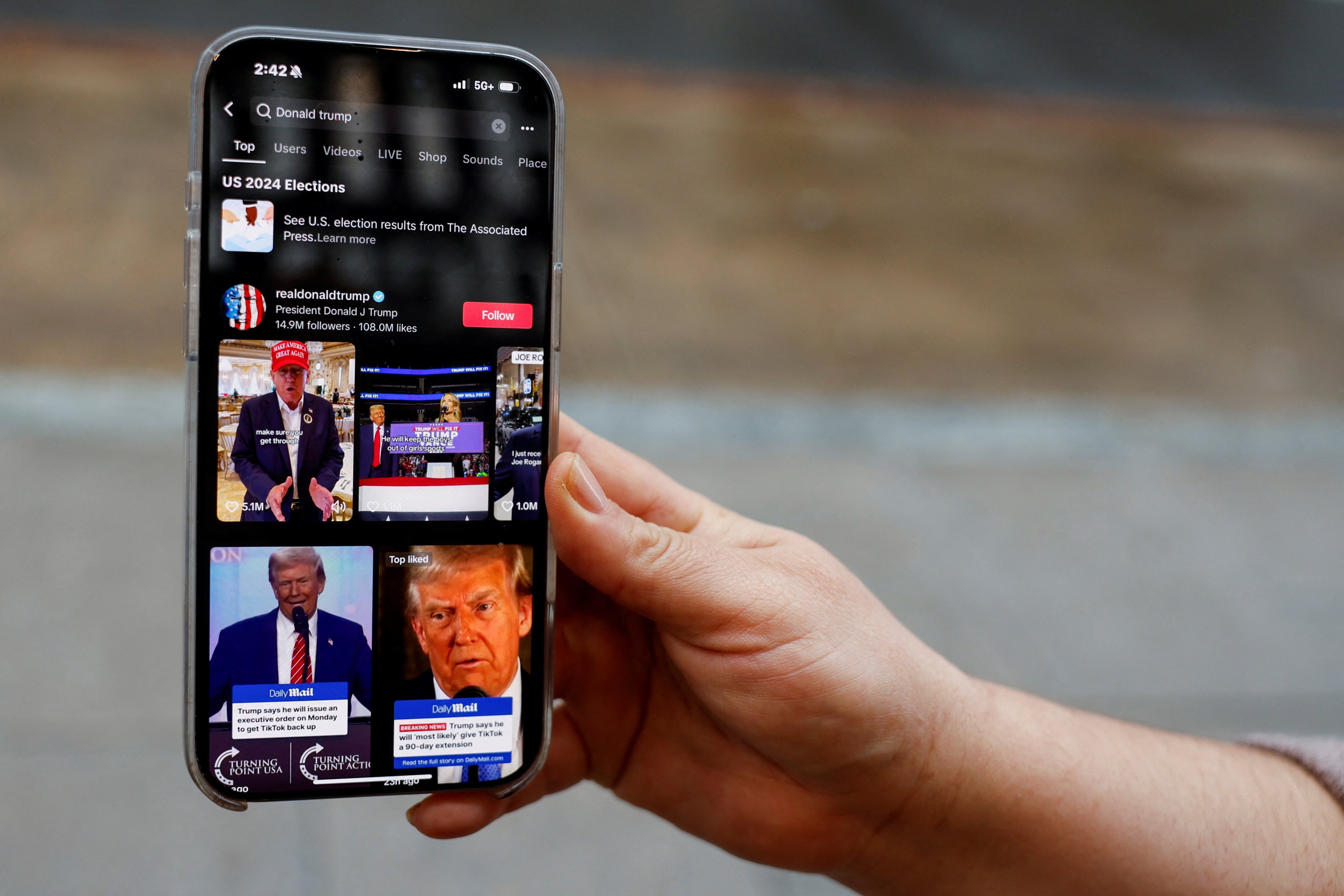 A woman poses with her smartphone displaying the @realdonaldtrump TikTok page on January 19. Photo: Reuters