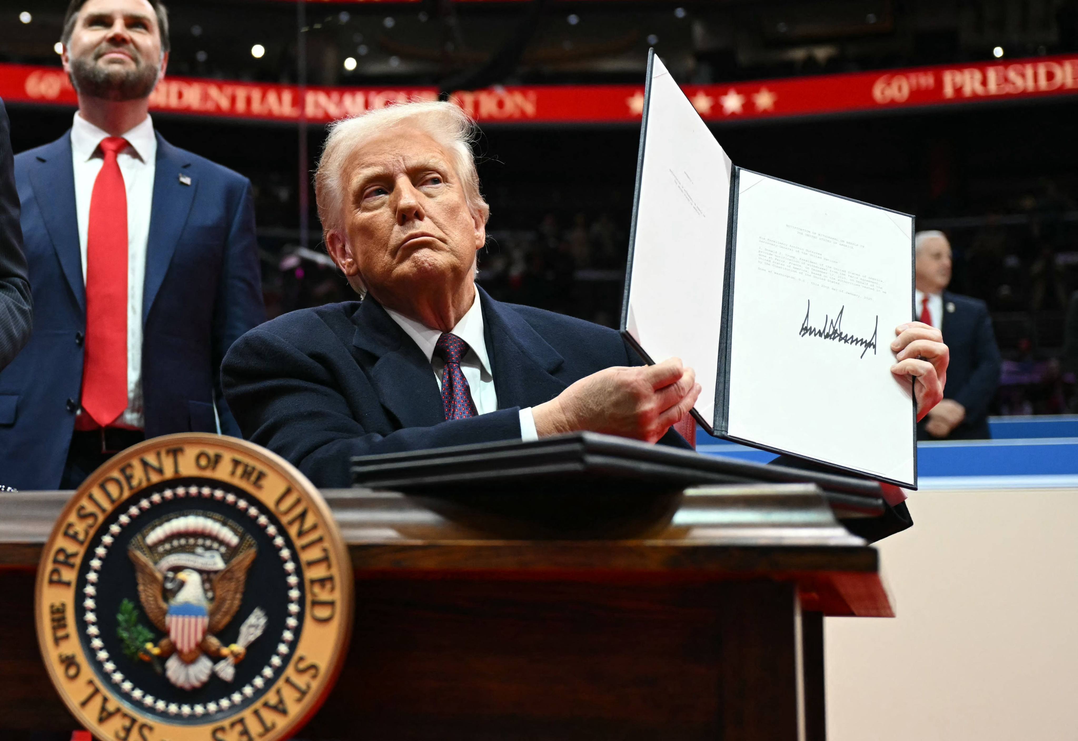 US President Donald Trump holds up a letter to the UN stating that the US will withdraw from the Paris Agreement during his inaugural parade inside Capital One Arena, in Washington on Monday. Photo: AFP