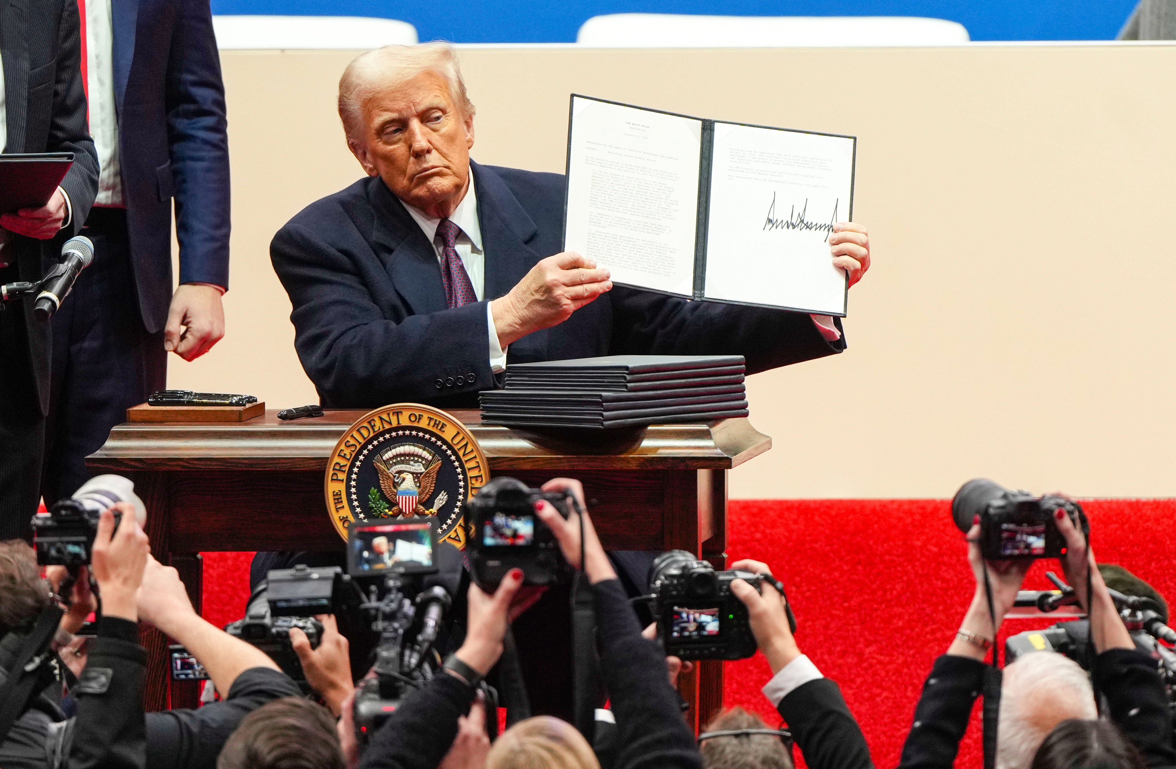 US President Donald Trump holds up an executive order after signing it at an indoor presidential inauguration event in Washington on Monday. Photo: AP