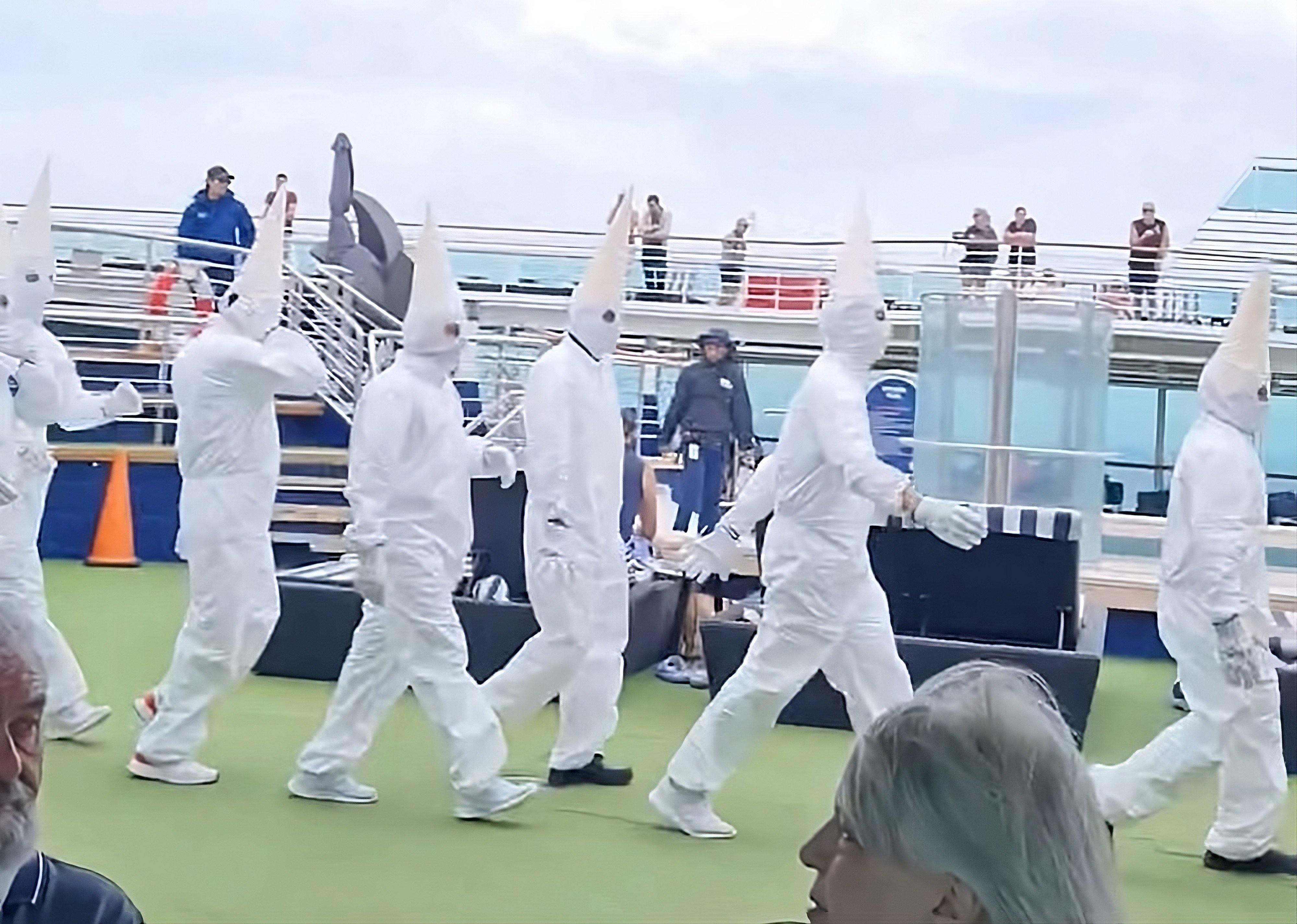 A still from a social media video shows staff strolling across the deck of an Australian cruise liner in all-white jumpsuits and cone-shaped hats evoking the distinctive white robes and masked hoods worn by the racist Ku Klux Klan. Photo: X/LidZen5