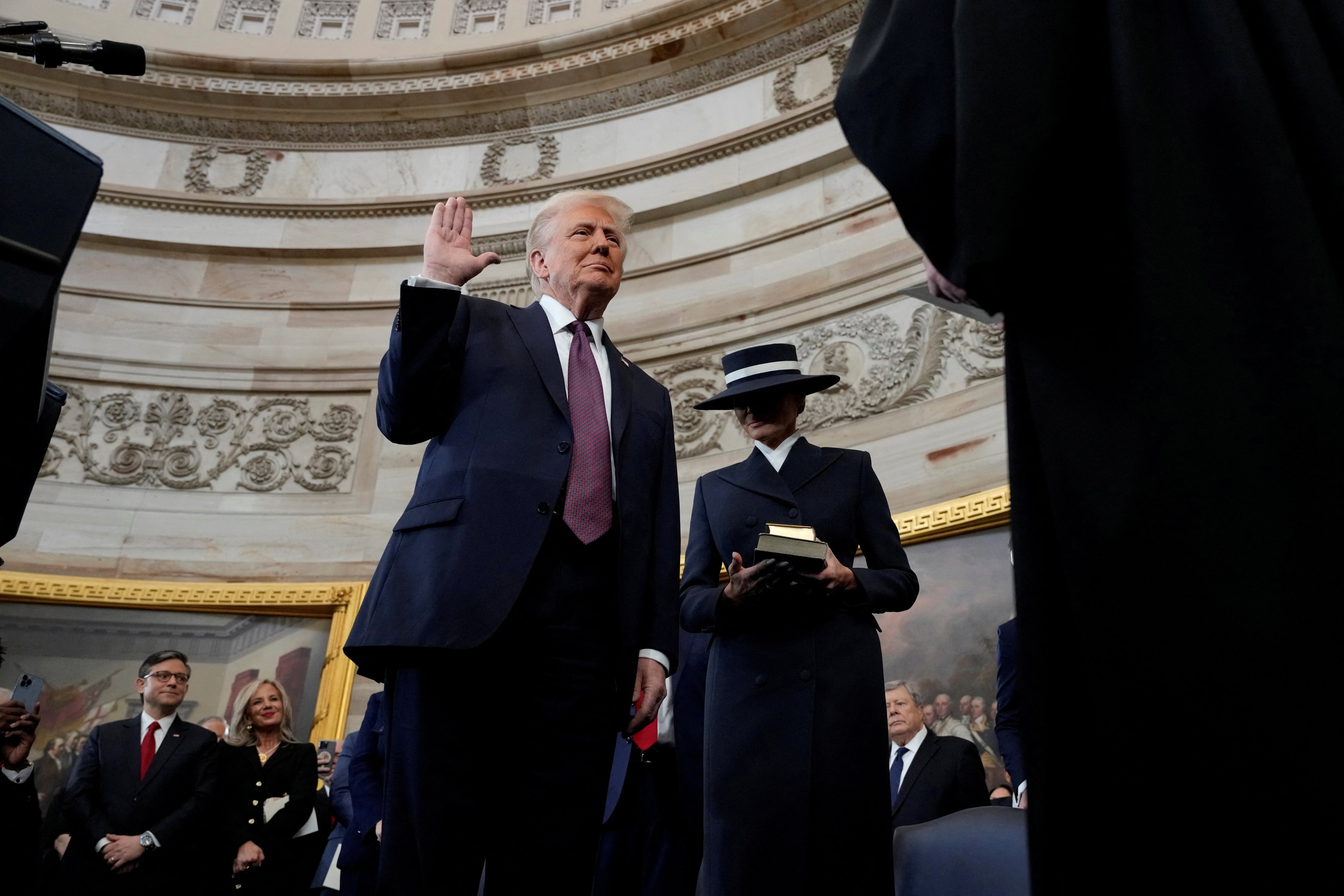 Donald Trump raises his hand as he waits to be sworn in as the 47th president of the United States and Melania Trump holds the Bible in the rotunda of the US Capitol in Washington on January 20. Photo: Reuters