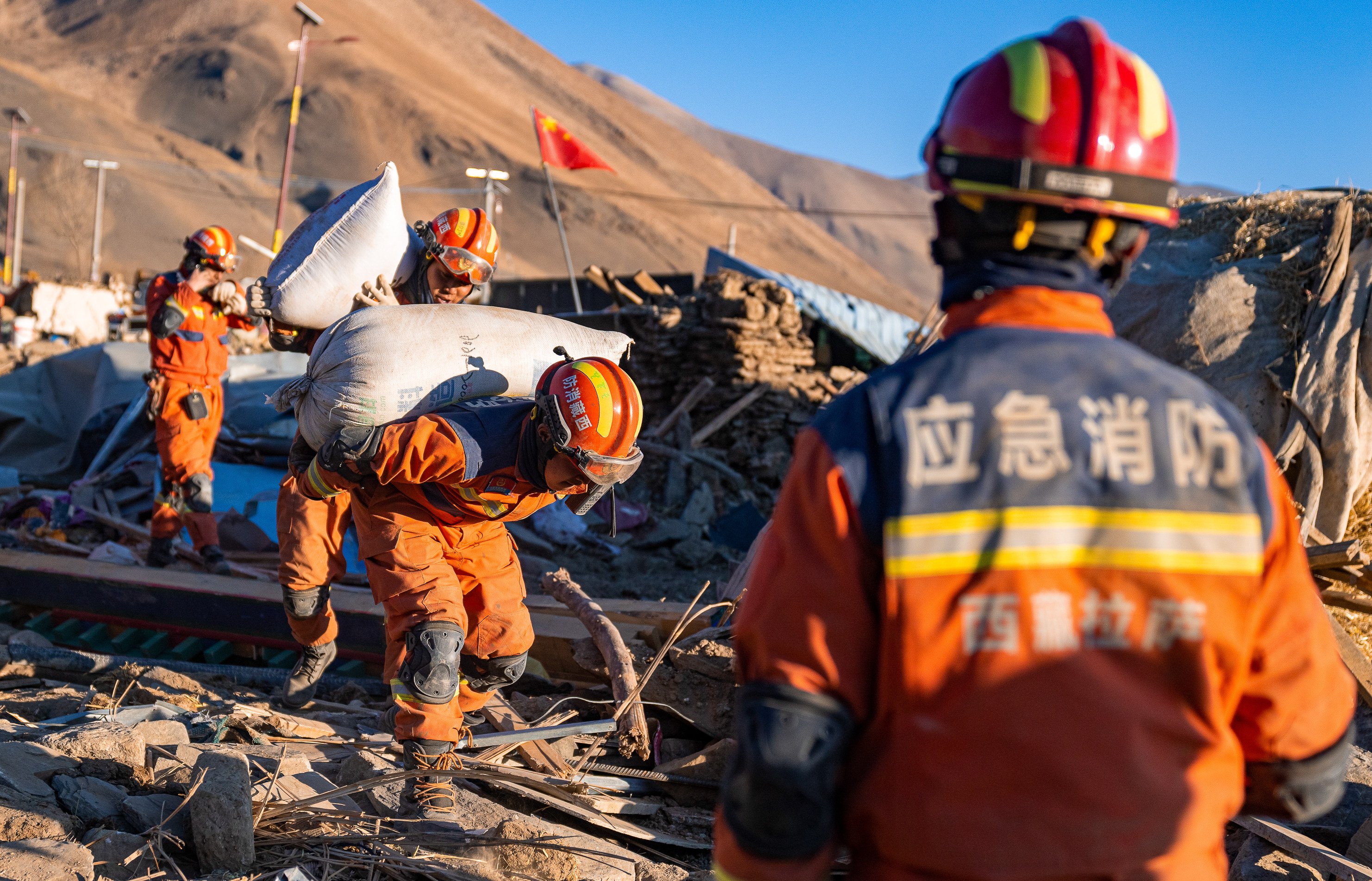 Firefighters carry barley in the village of Gurong, in Dingri county, Tibet, following a magnitude 6.8 earthquake on January 7. The quake caused extensive damage to communication infrastructure. Photo: Xinhua