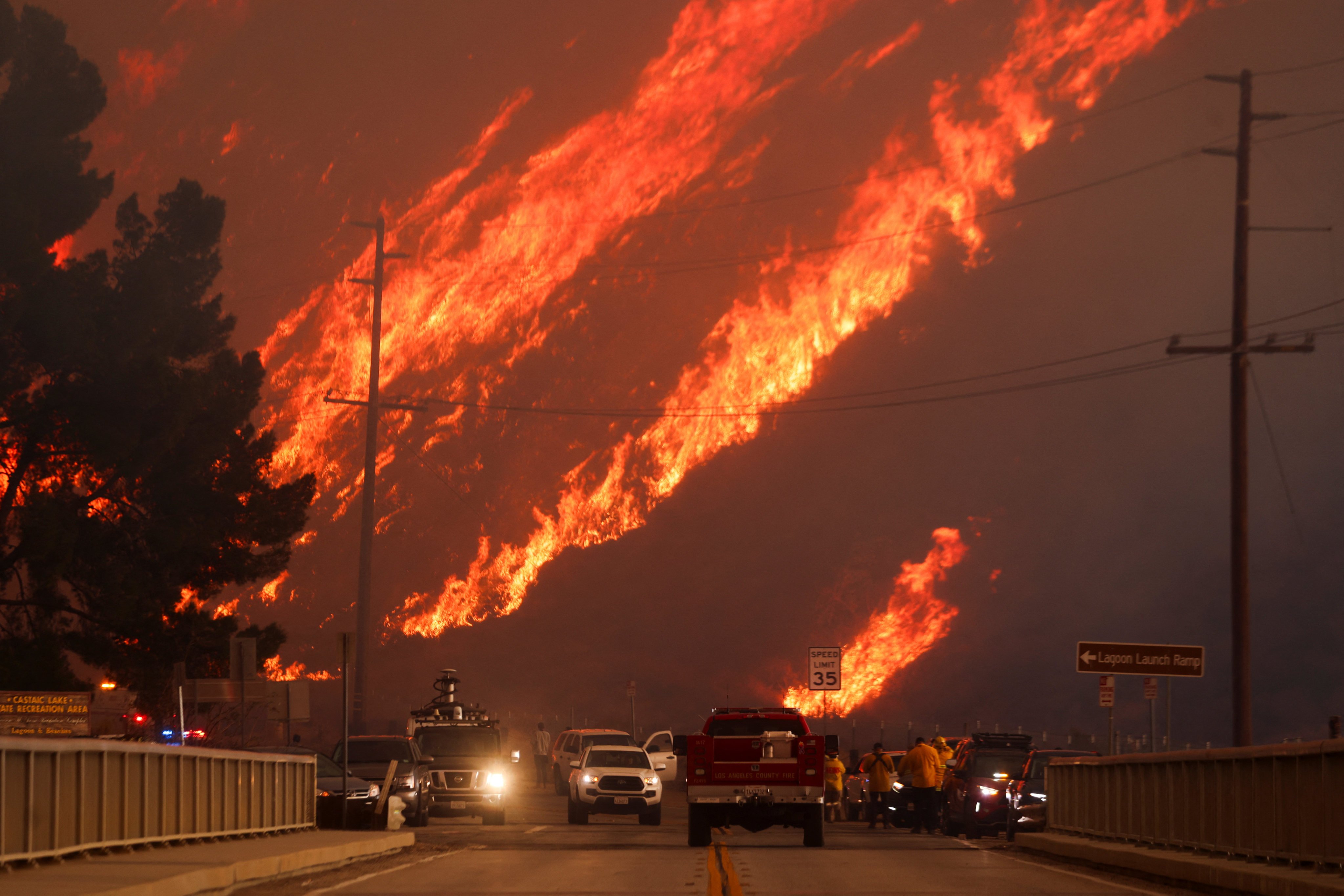 Flames rise behind vehicles as the Hughes Fire burns in Castaic Lake, California. Photo: Reuters