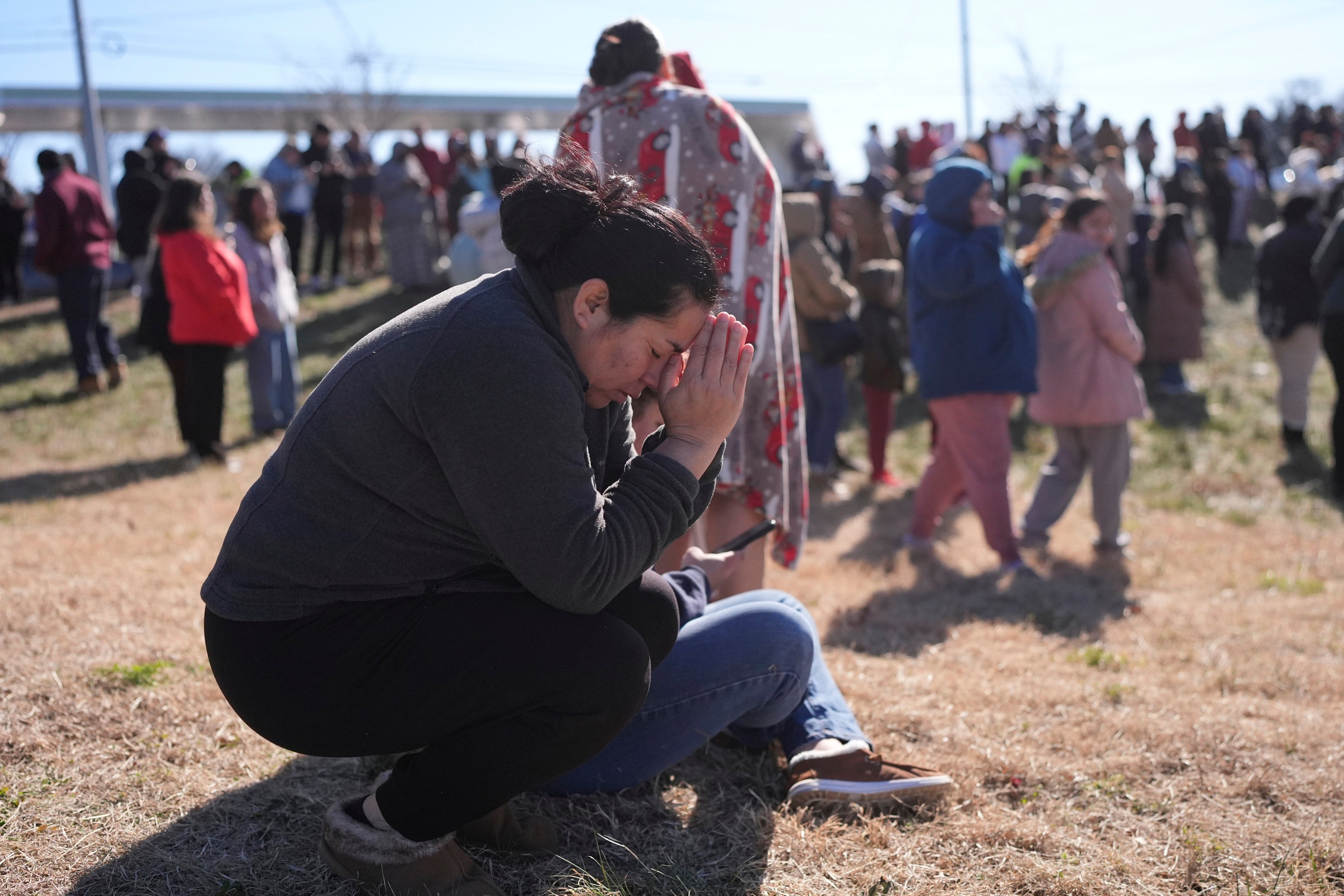 A parent prays as she waits for her daughter at a reunification site following the shooting. Photo: AP