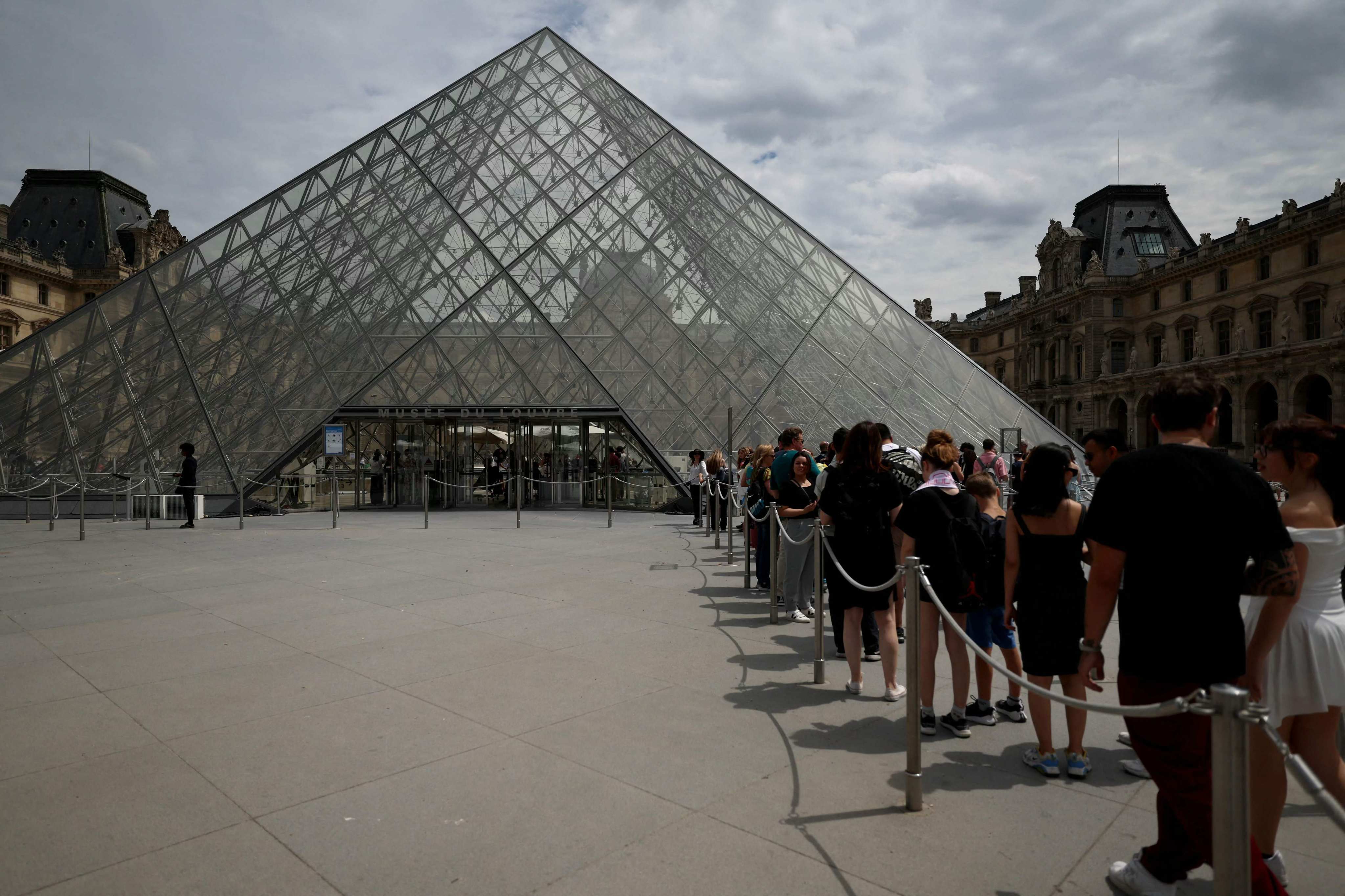 Visitors line up in front of the Louvre Pyramid in Paris in July 2024. Photo: AFP