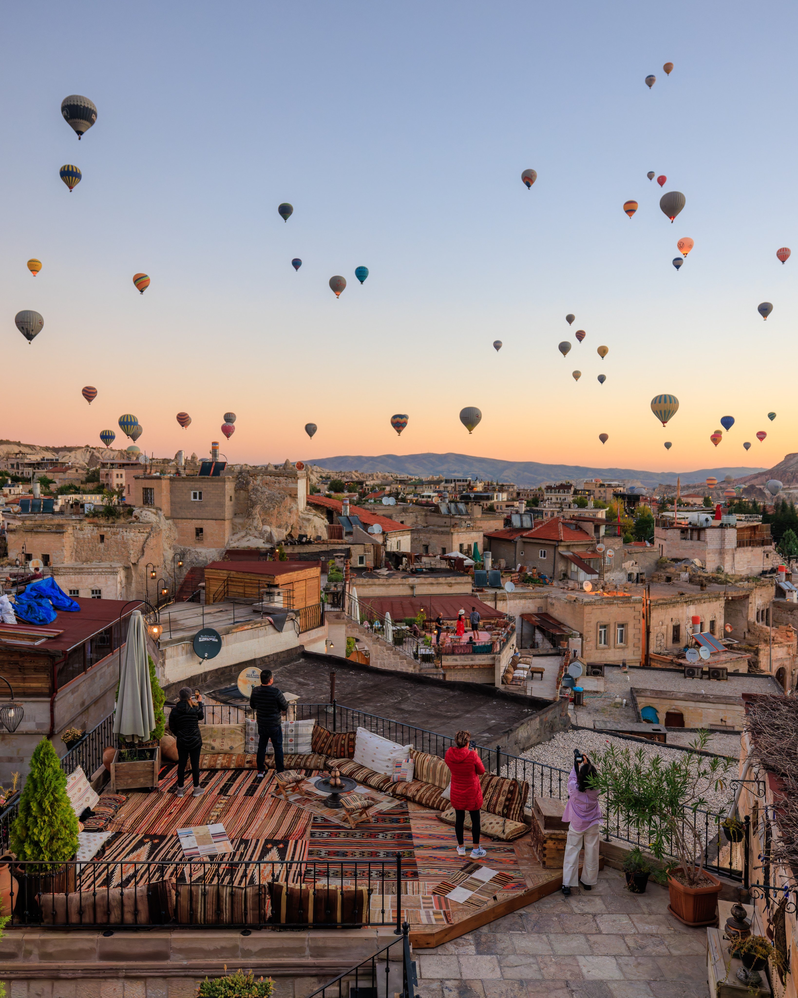 Travellers taking photos of hot-air balloons in flight in the town of Göreme in the early morning in Turkey. Photo: Shutterstock