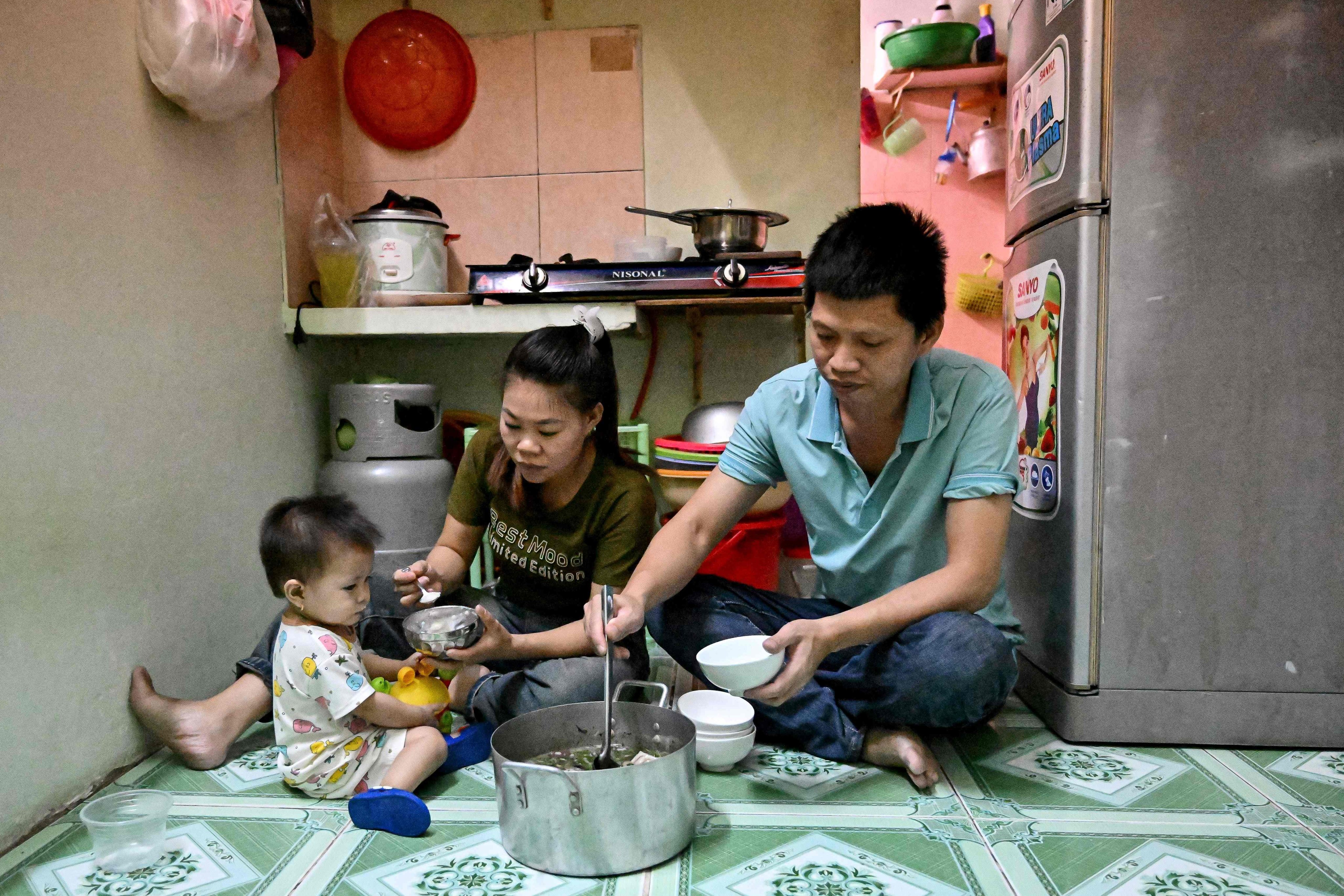 This photo taken on December 21, 2024 shows Truong Thi Le, who works at Taiwanese shoemaker Pou Chen’s Pouyuen Vietnam factory, having dinner with her husband and daughter inside their apartment in Ho Chi Minh City. Vietnam is among the world’s largest exporters of clothing, footwear and furniture and Ho Chi Minh City and its hundreds of thousands of migrant workers have for decades helped power its manufacturing boom. But as living costs surge, a wave of workers are rejecting the commercial hub for a quieter life back home -- leaving city businesses struggling to fill their ranks. (Photo by Nhac NGUYEN / AFP) / TO GO WITH: Vietnam-economy-labour-lifestyle, FOCUS by Tran Thi Minh Ha