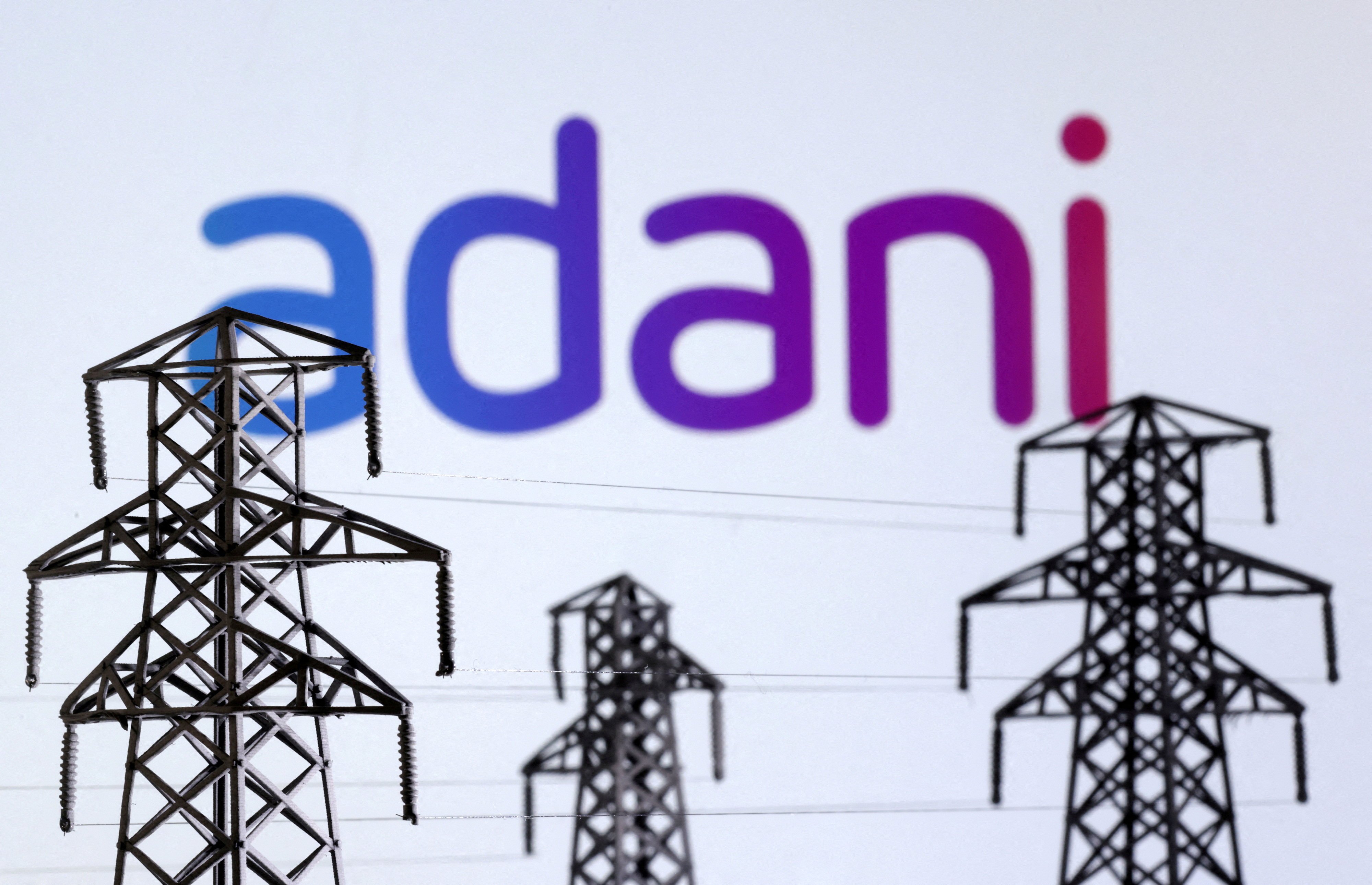 Electric power transmission pylon miniatures and the Adani Green Energy logo. Photo: Reuters