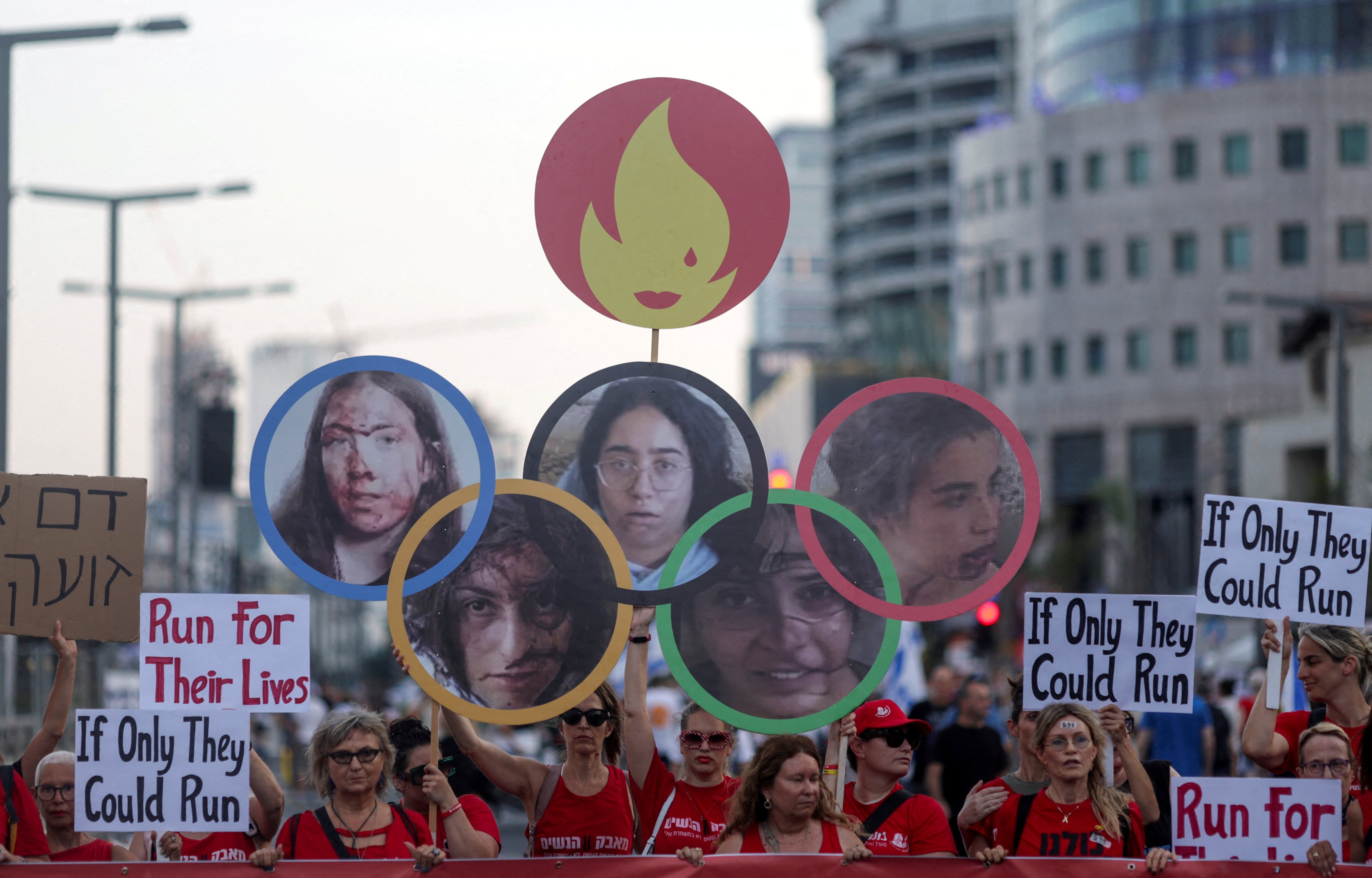 Demonstrators hold up a cut out of the Olympic rings with pictures of hostages Liri Elbag, Naama Levy, Karina Ariev, Daniela Gilboa and Agam Berger attached to the hoops in Tel Aviv, Israel, in July 2024. Photo: Reuters