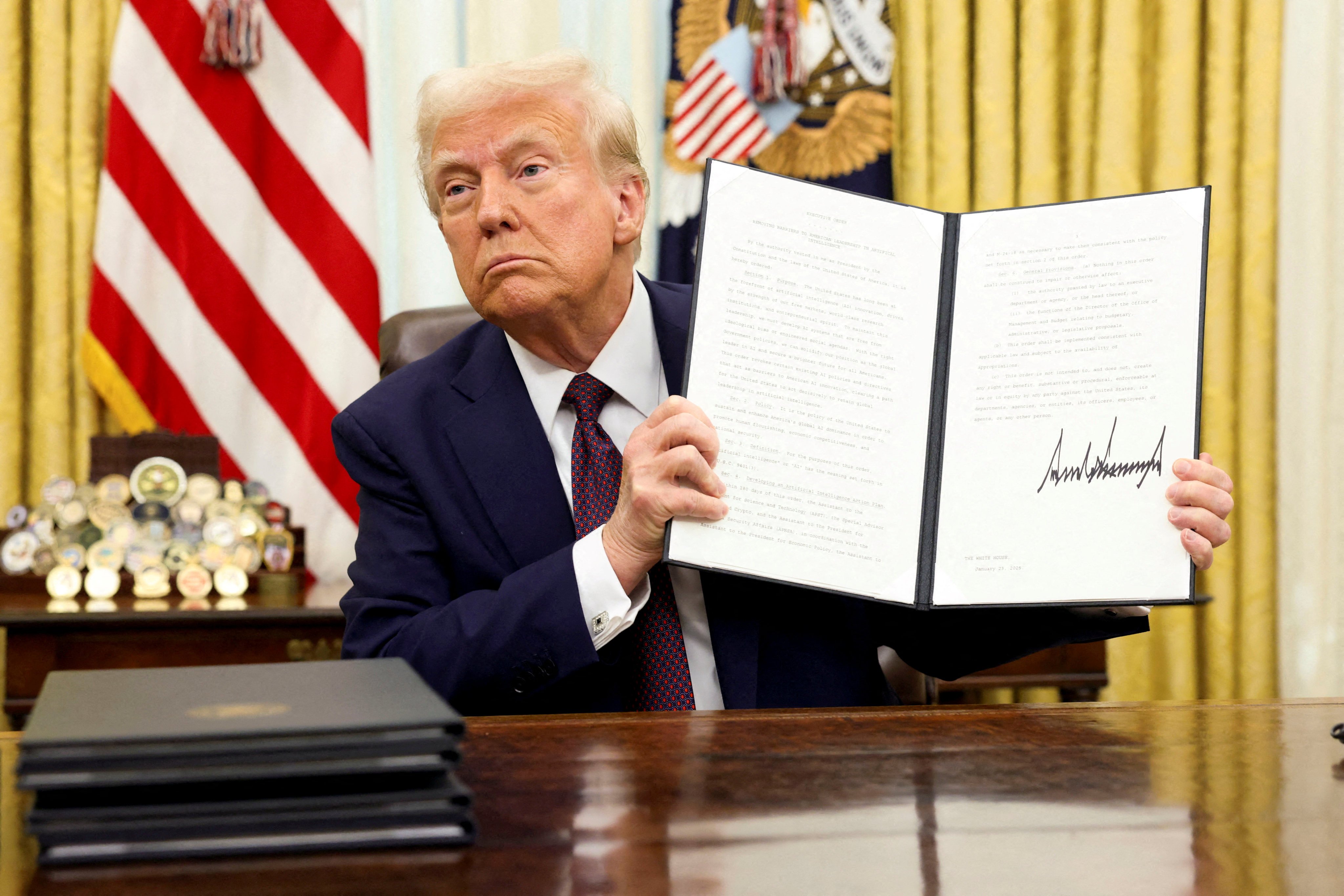 US President Donald Trump holds a signed executive order on AI, in the Oval Office of the White House, in Washington, US, on Tuesday. Photo Reuters