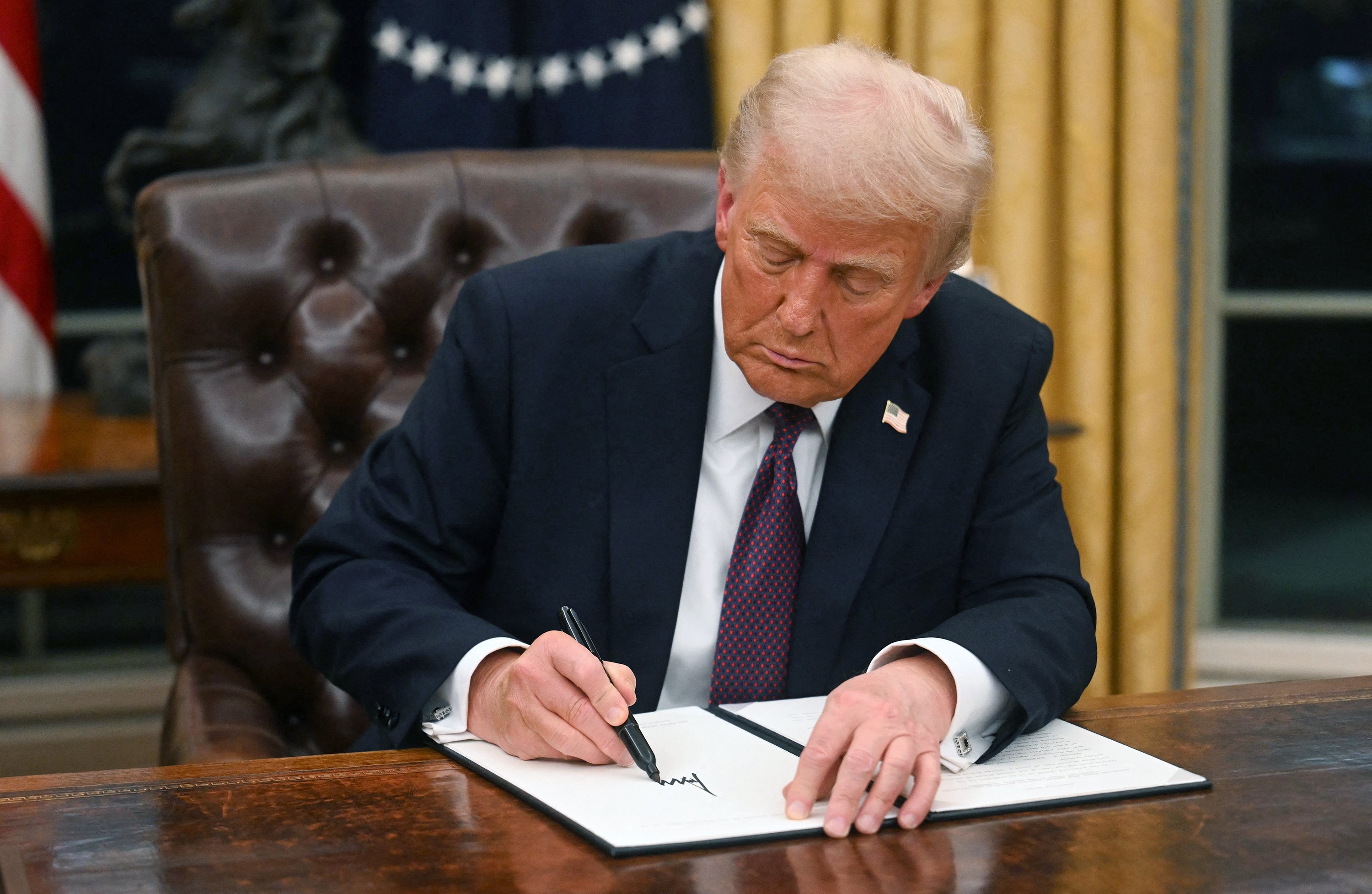 US President Donald Trump signs an executive order in the Oval Office of the White House in Washington on January 20. Photo: Getty Images