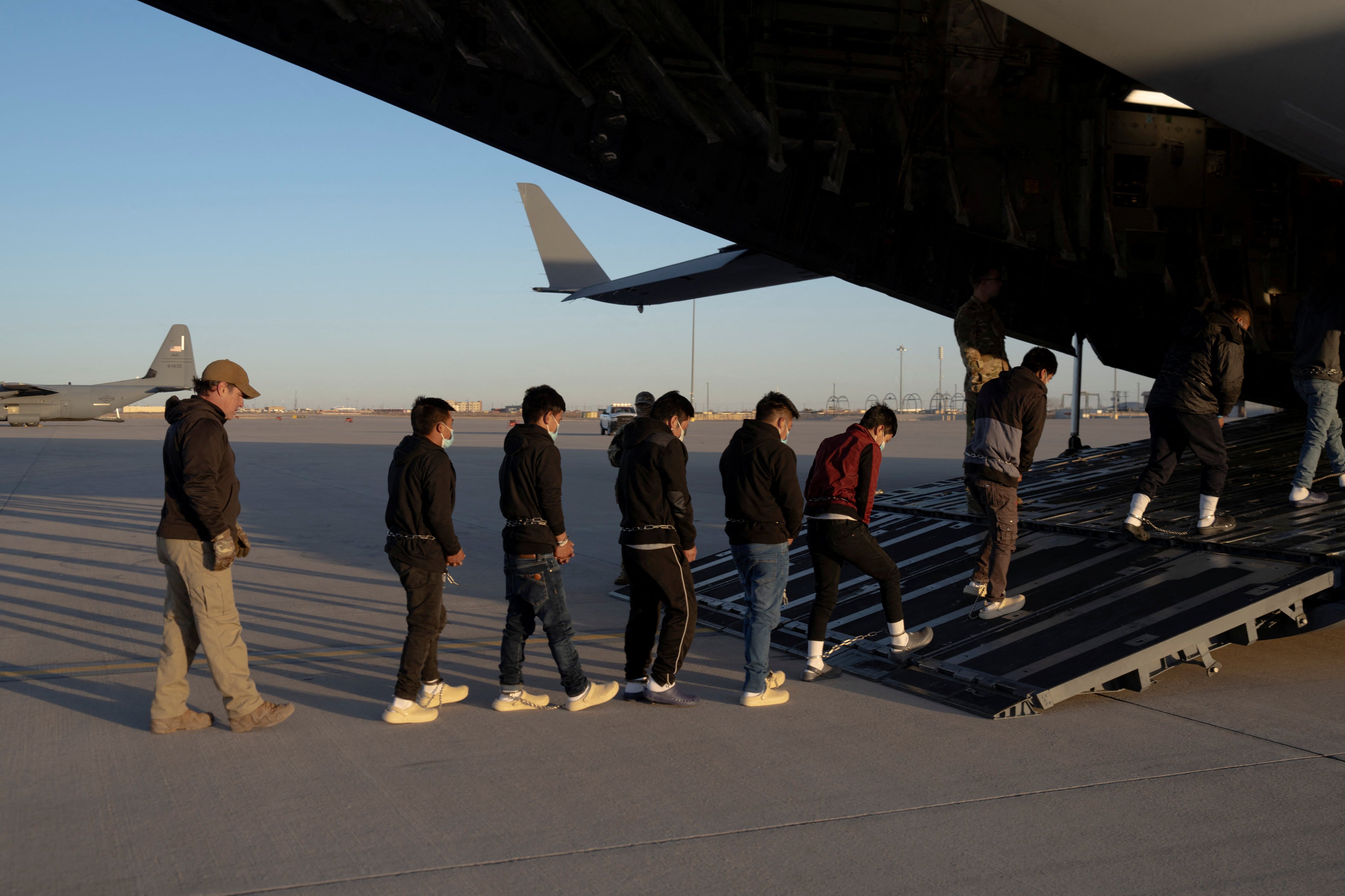 US security agents guide detained migrants to board a US Air Force C-17 Globemaster III aircraft for a removal flight at Fort Bliss, Texas. Photo: Department of Defence via Reuters