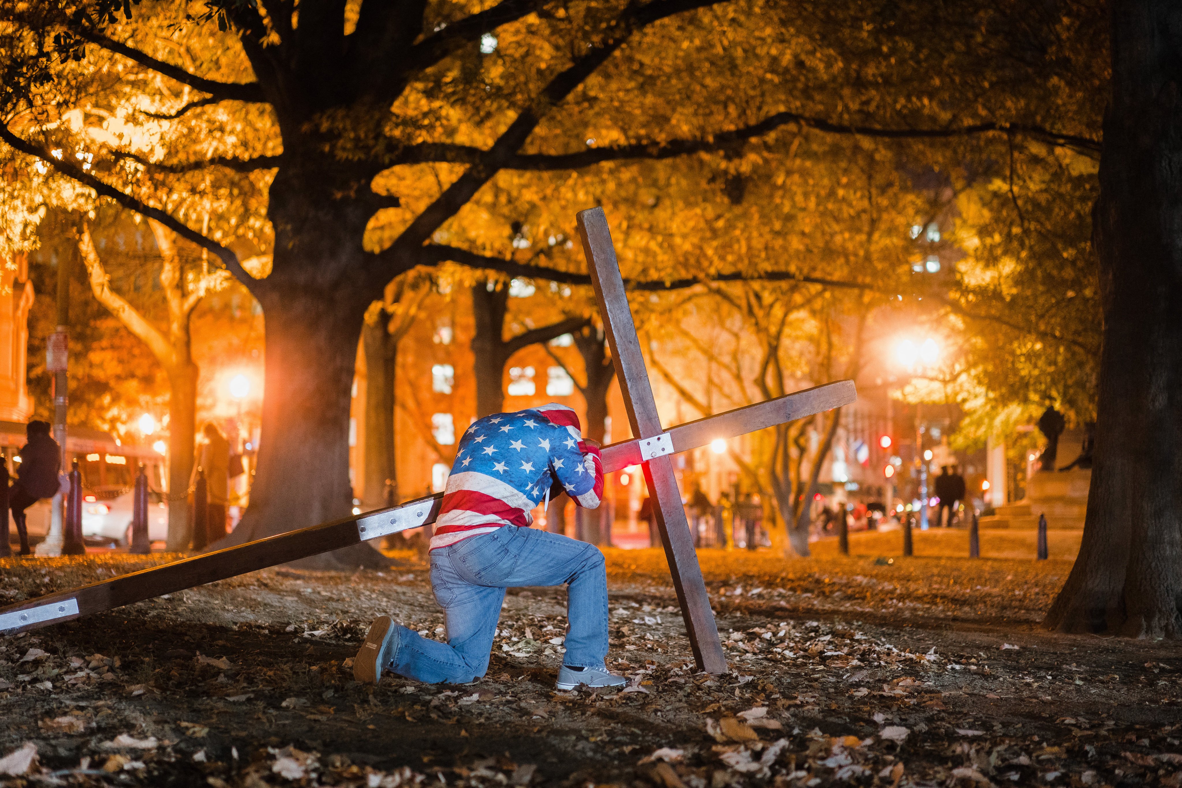 A man kneels next to a cross in Washington on November 9, 2016, as part of a gathering to pray for the protection of the White House and democracy after Donald Trump’s election that year. Photo: AFP