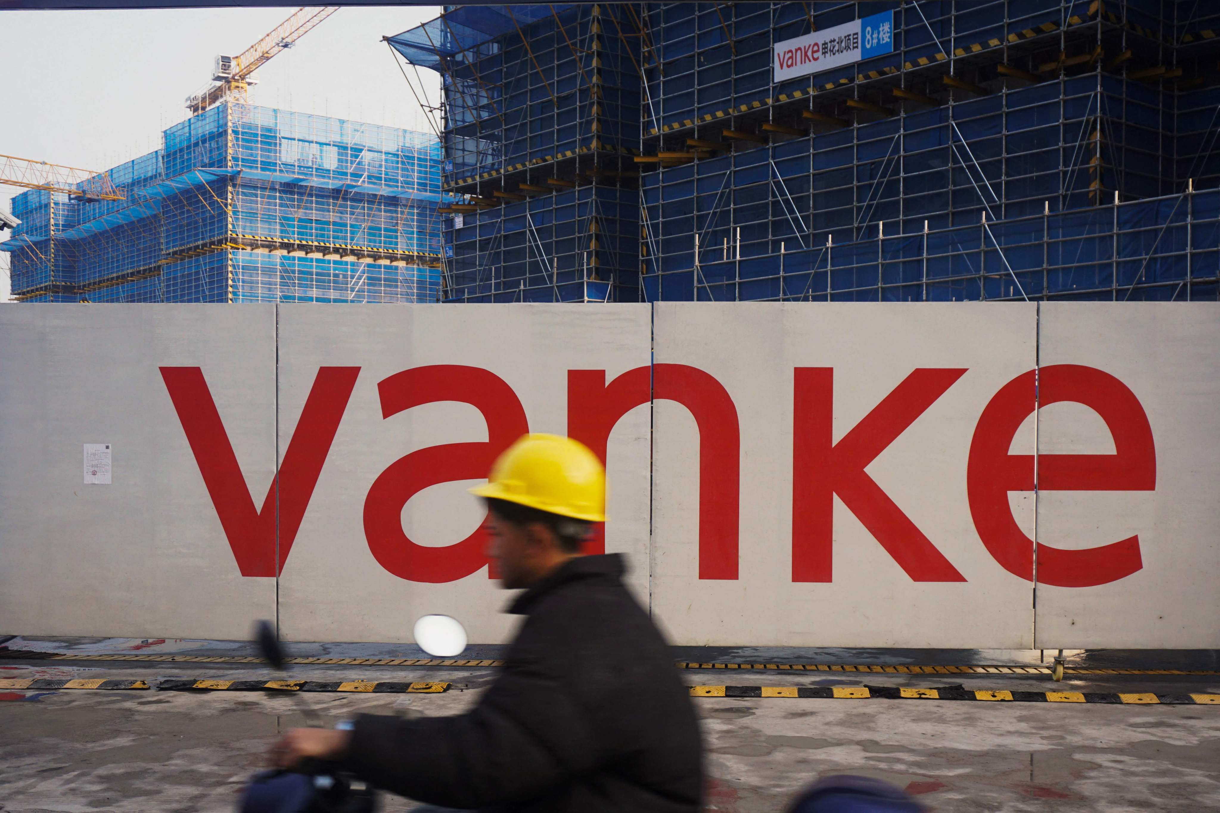 A photo taken on March 31, 2024, shows a worker driving past residential buildings under construction by Chinese real estate developer Vanke in Hangzhou, in eastern China’s Zhejiang province. Photo: AFP