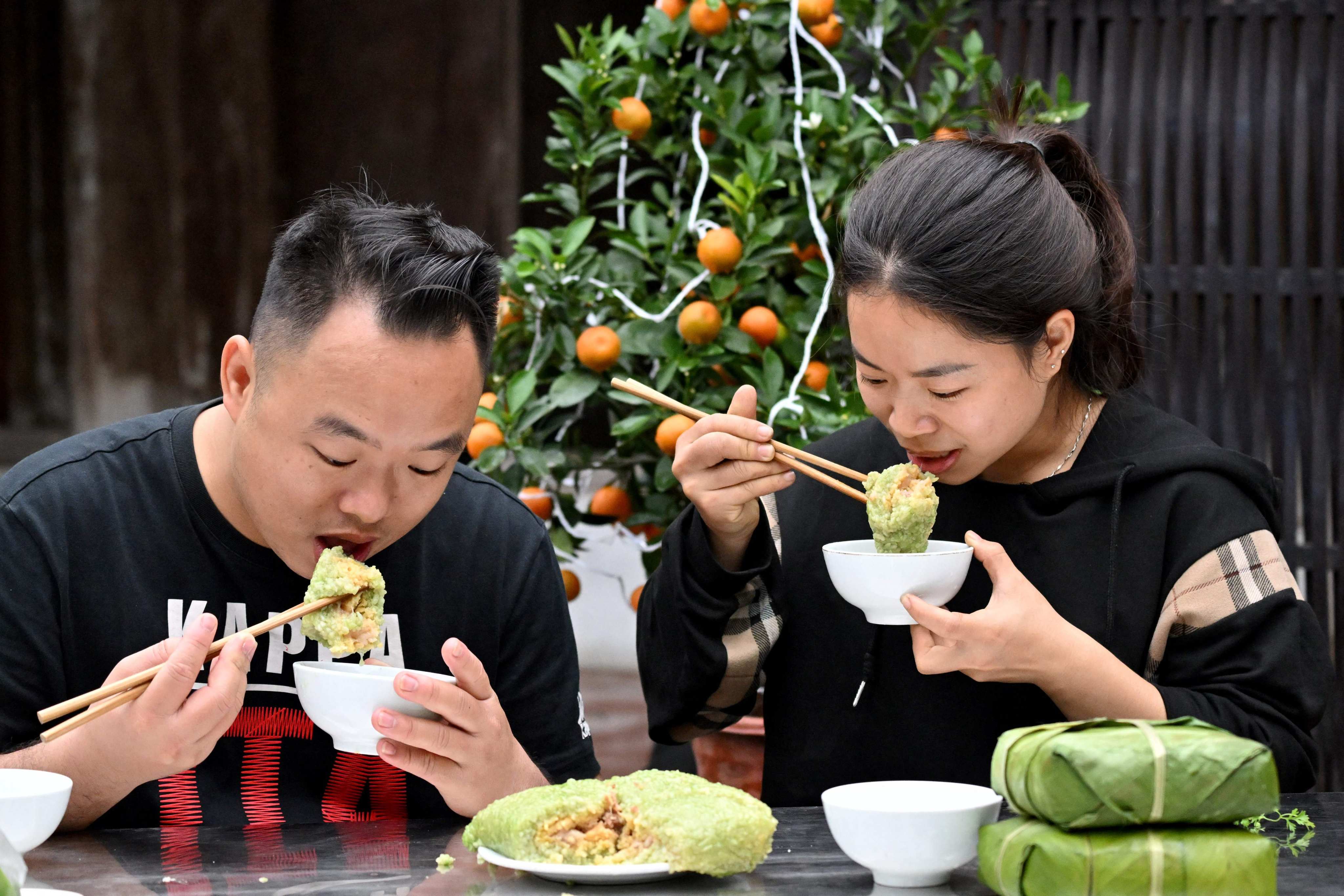 A couple eat “banh chung” at their home in Hanoi. Photo: AFP