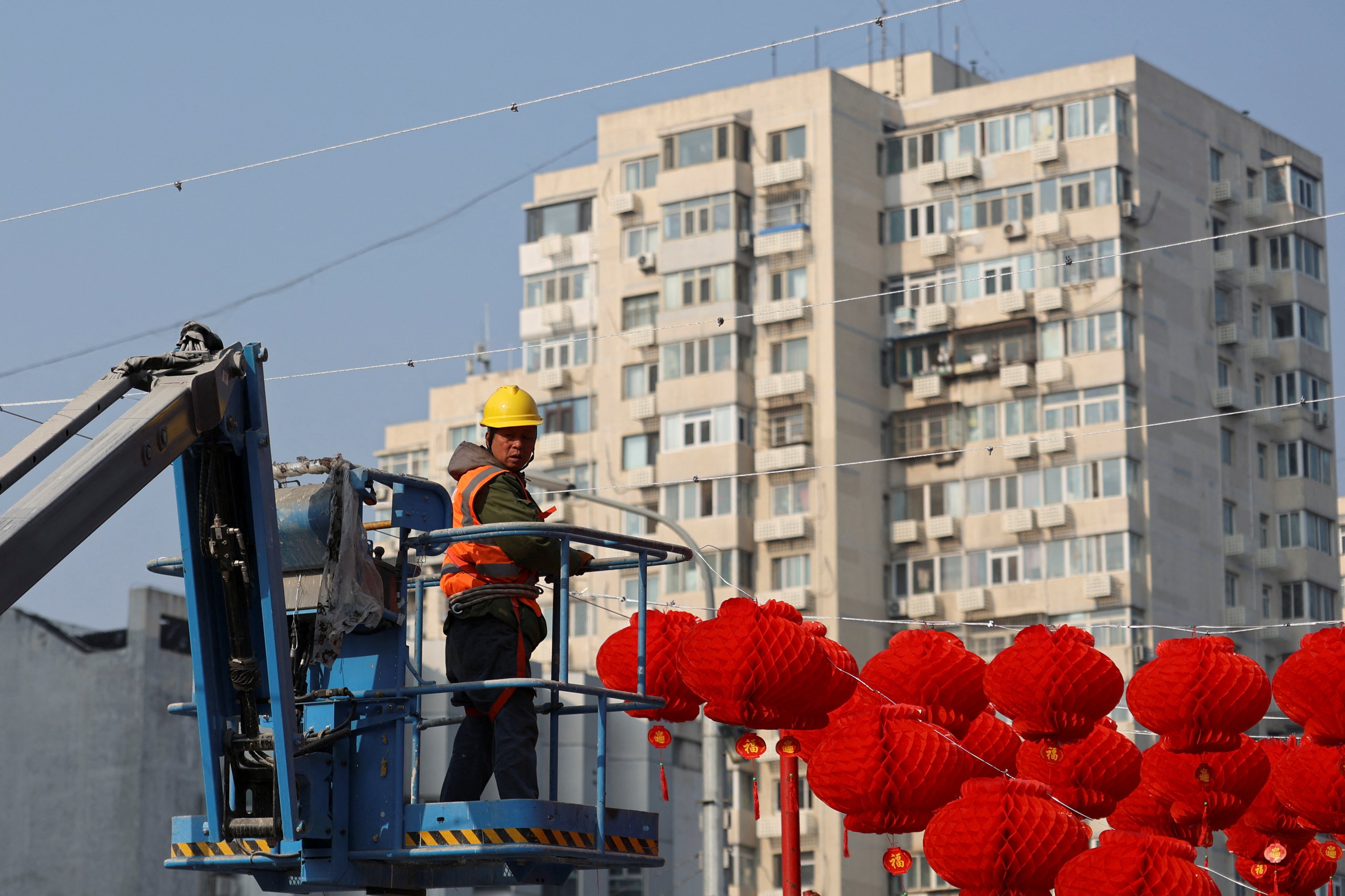 A worker stands on a crane as he installs red lanterns outside a park before the Lunar New Year celebrations in Beijing on January 24, 2025. Photo: Reuters