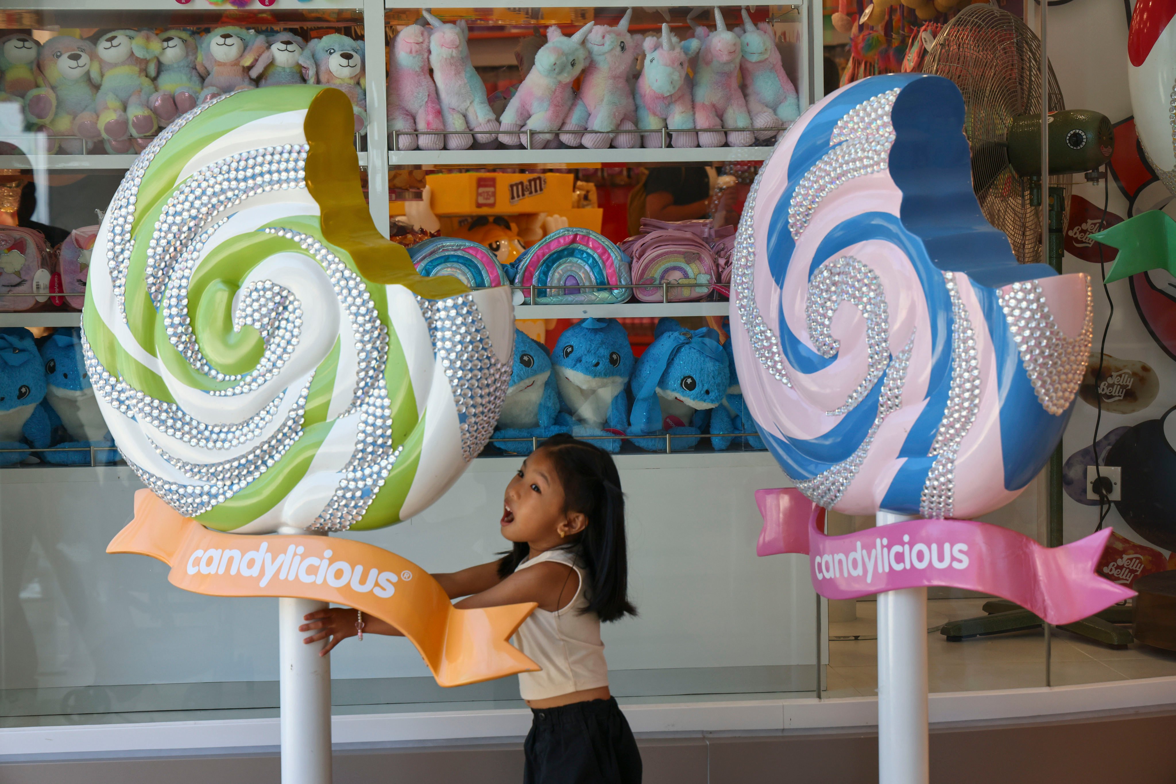 A girl plays among candy decorations outside a shop at Peak Galleria in Hong Kong on August 4, 2024. Photo: Dickson Lee