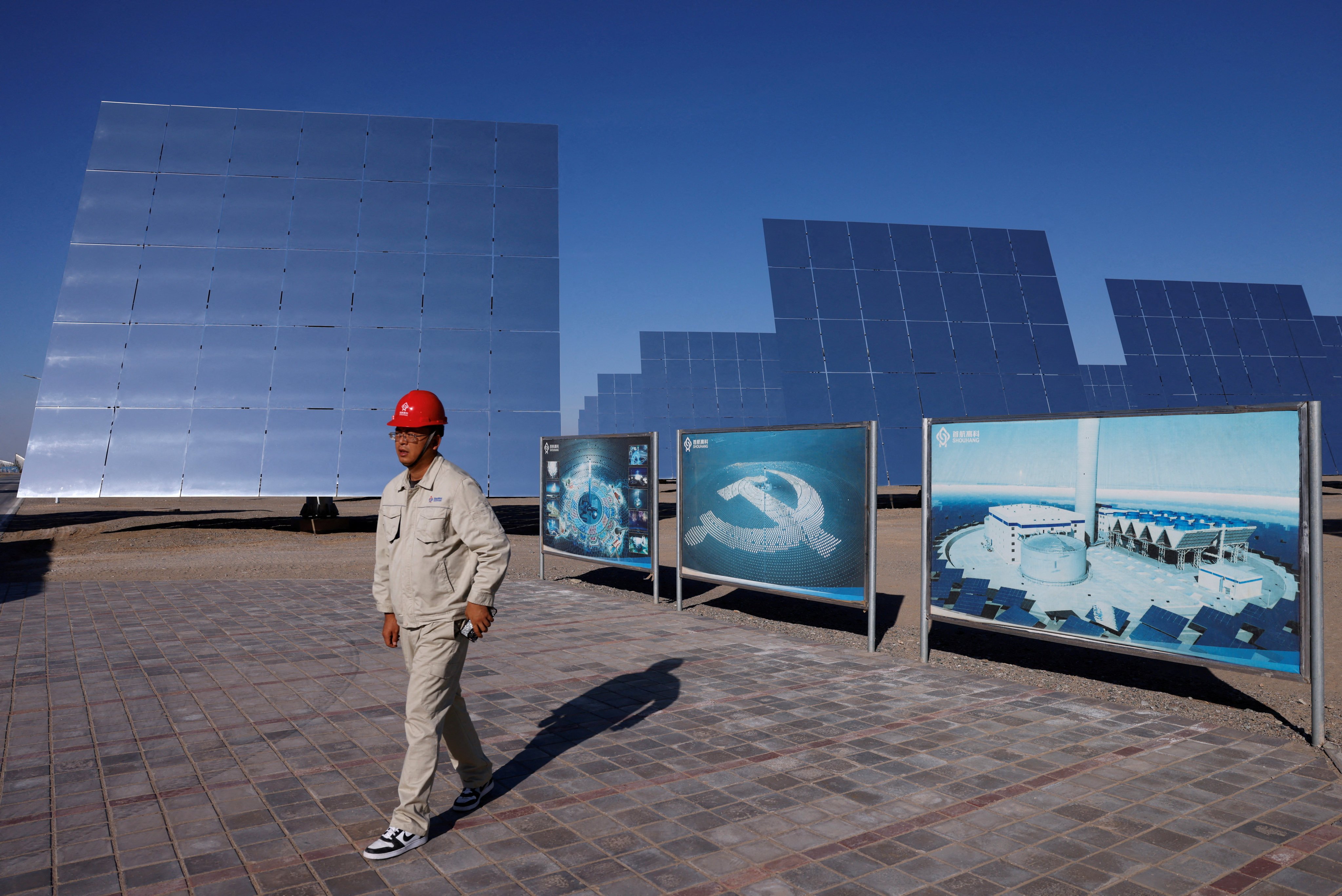 An employee walks near fields of heliostat mirrors at the site of a solar project in Dunhuang, Gansu province, on October 16, 2024. Photo: Reuters