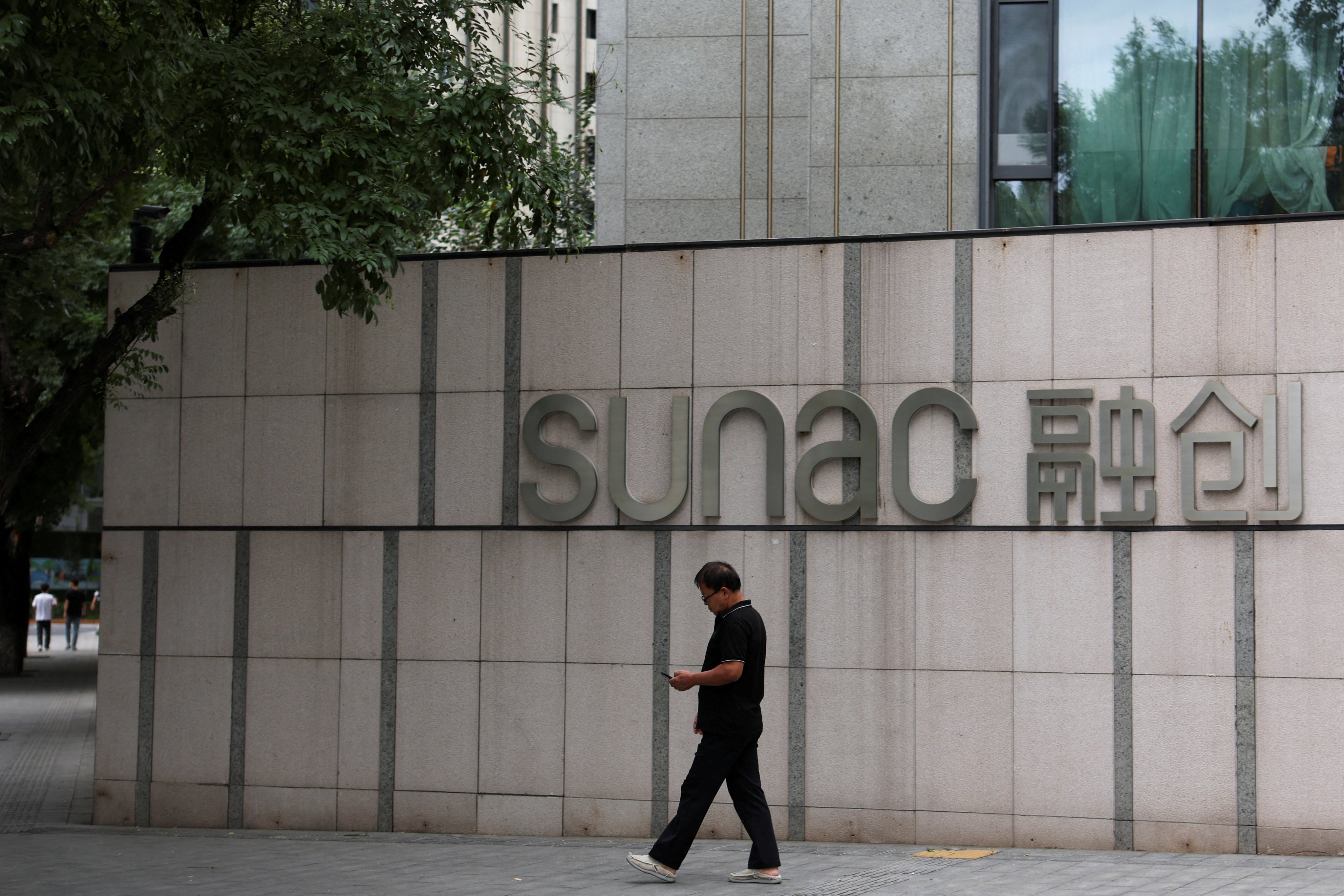 A man walks past the logo of property developer Sunac outside a residential compound in Beijing in September 2023. Photo: Reuters