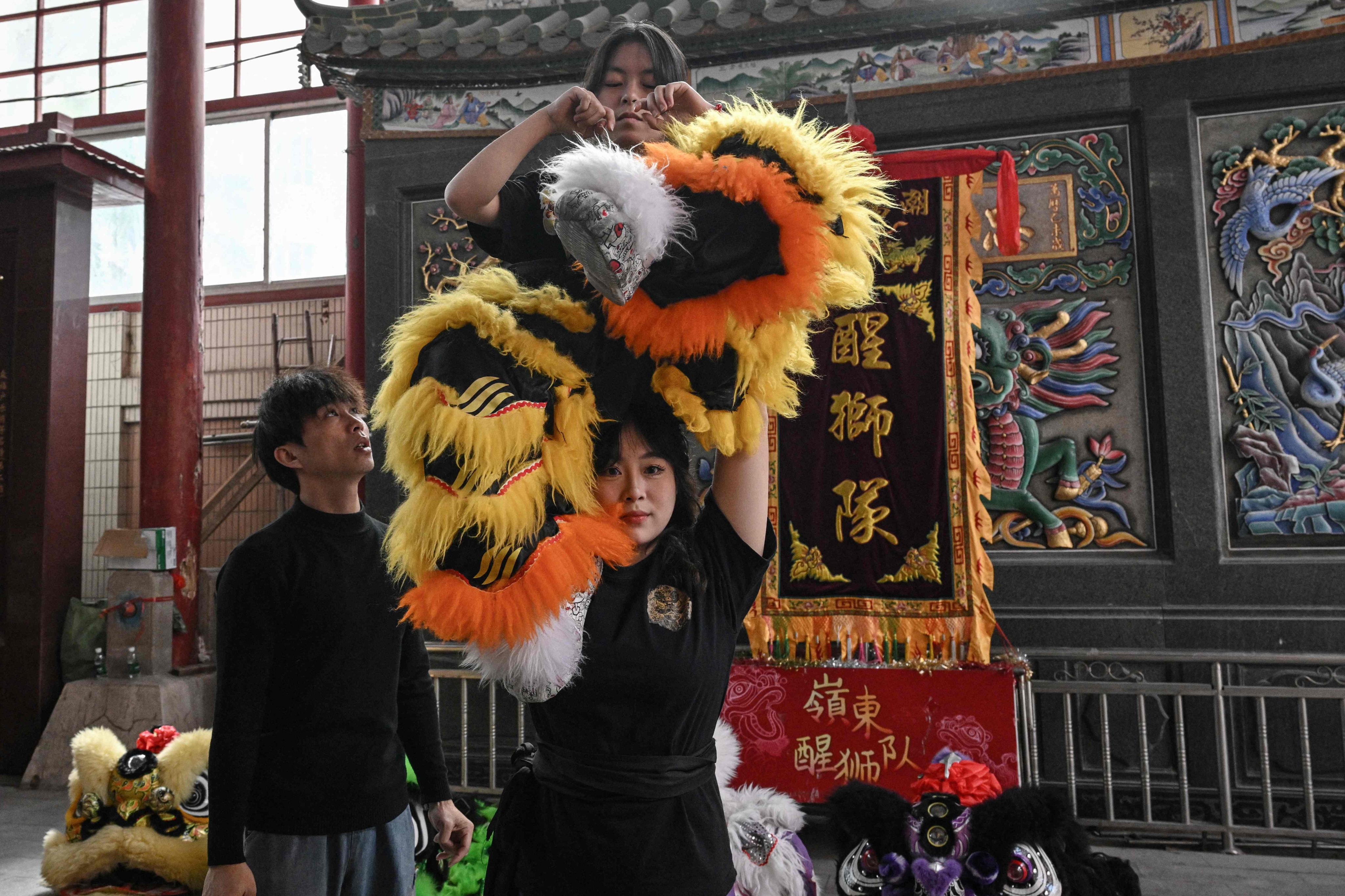 This photo taken on January 22, 2025 shows female lion dancers taking part in a practice session at an ancestral temple in Shantou, in southern China’s Guangdong province. Sporting furry sequinned trousers and a black training top, Lin Xinmeng flings her male teammate into the air -- part of China’s world-renowned lion dance that is shrugging off centuries of patriarchal norms. Performed across China and around the world, at weddings or during business openings, it is a mainstay festivity for the Lunar New Year which which falls on January 29 this year. (Photo by Jade GAO / AFP) / TO GO WITH: China-culture-LNY-dance-lion, REPORTAGE by Ludovic EHRET