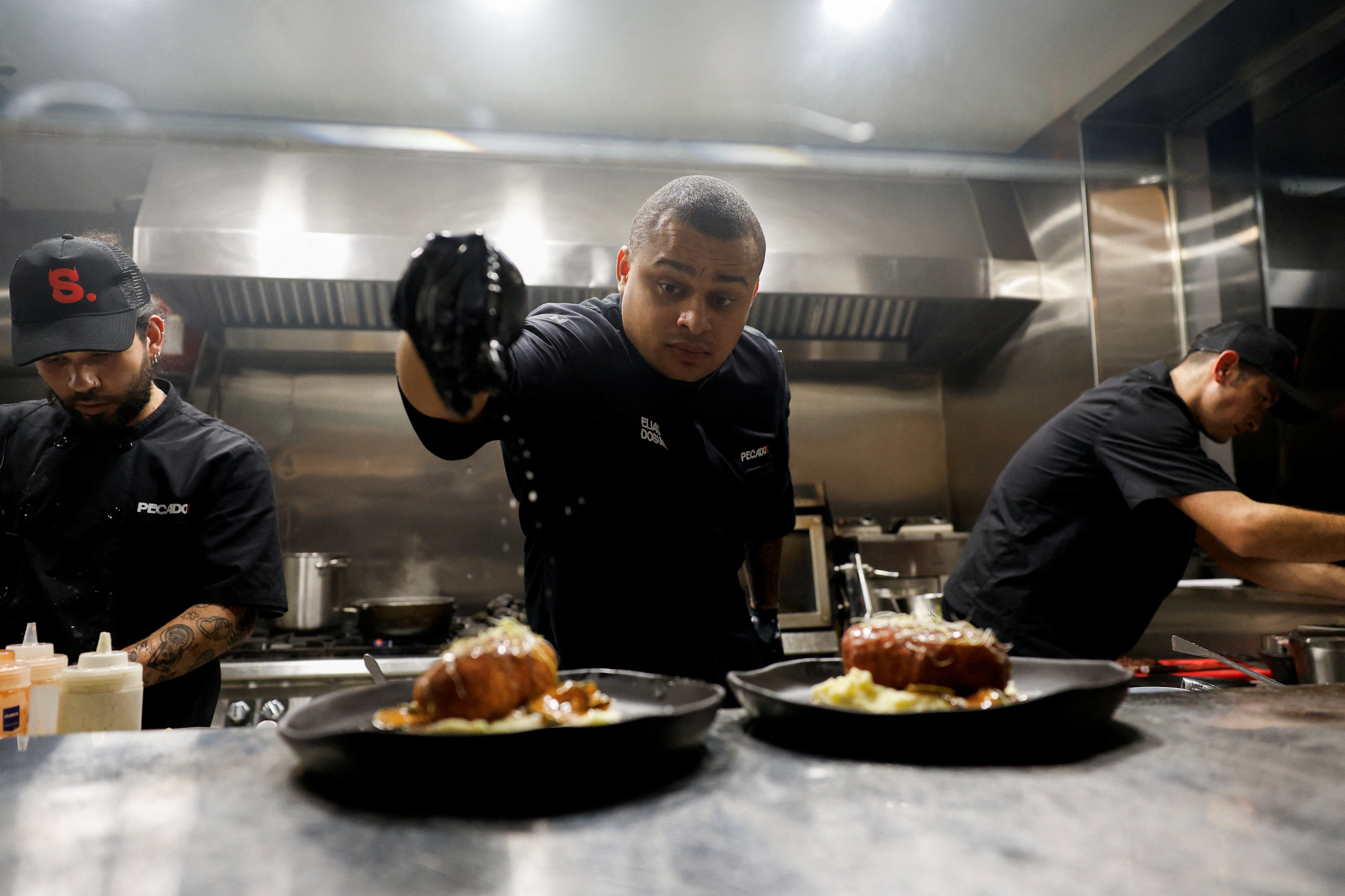 Elias Dosunmu puts salt on dishes in his restaurant in Madrid, Spain. Photo: Reuters